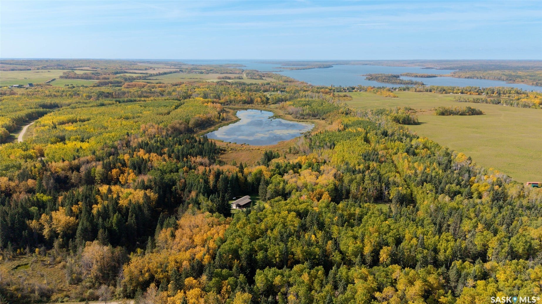 Extensive treed landscape, a distant body of water, and a remote dwelling