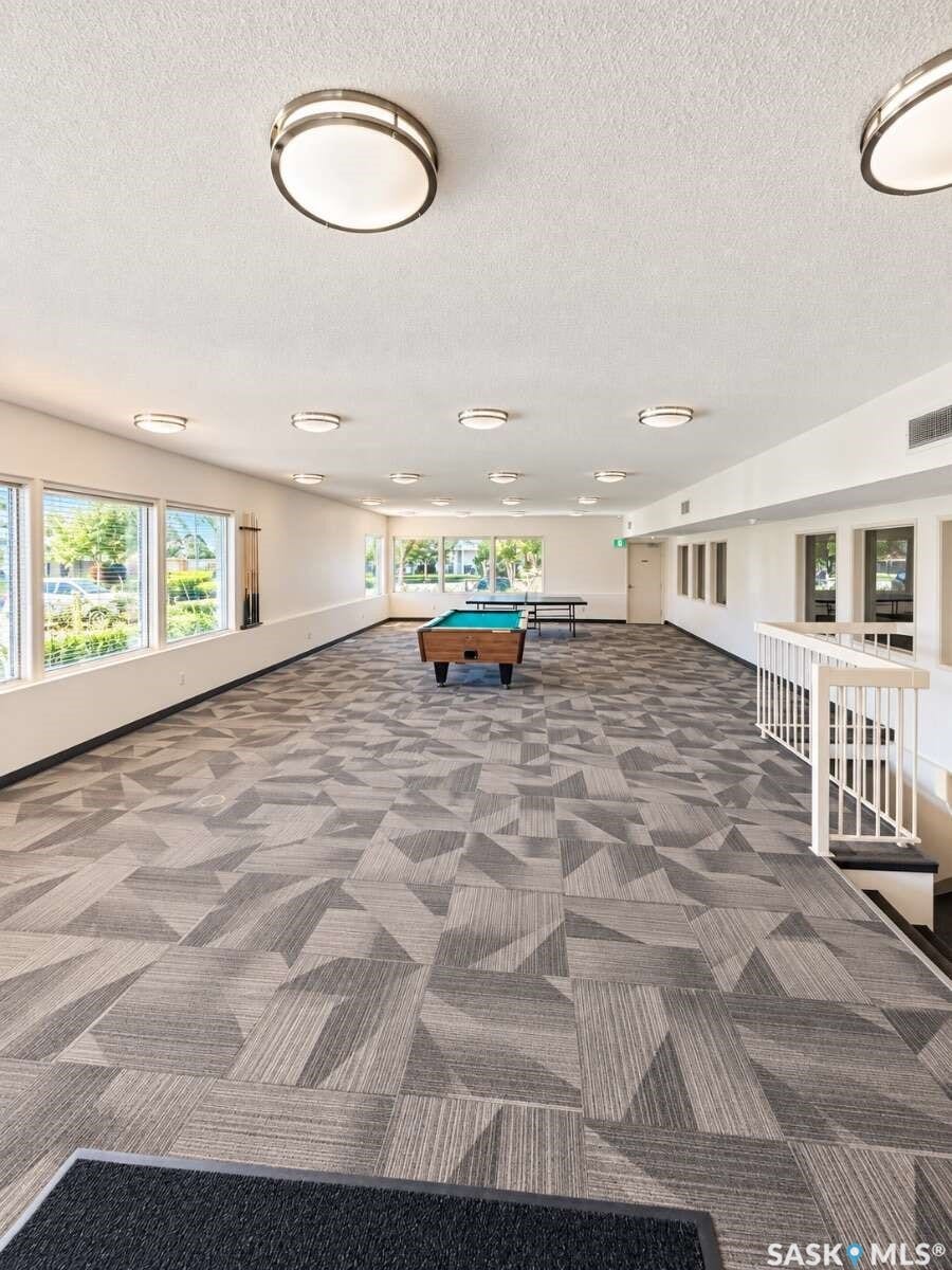 Spacious multi-purpose room featuring extensive window lines, patterned carpet flooring, and recessed lighting