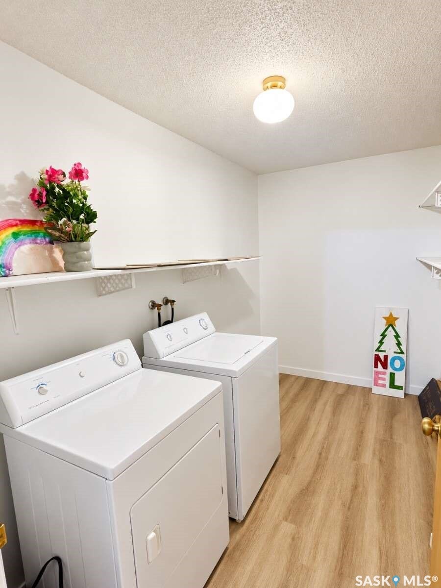 Laundry area featuring wood-finish flooring, a flush-mount ceiling light, and white wall shelving