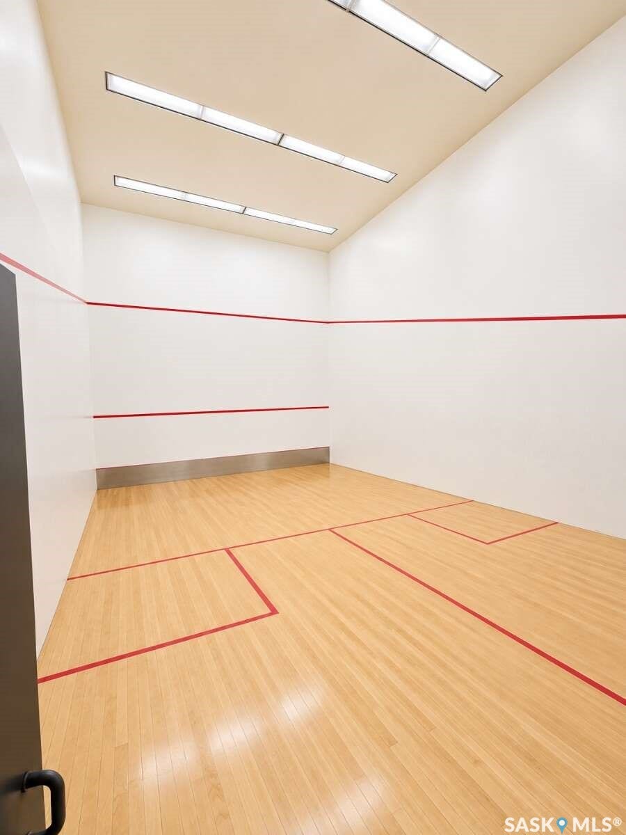 Indoor court featuring wood flooring with red court lines, white walls, and overhead lighting