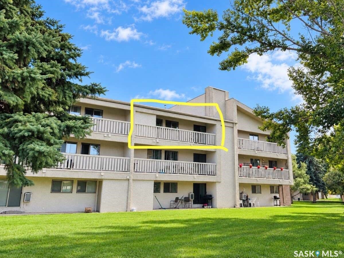 Building exterior featuring multiple private balconies, a manicured lawn, and mature trees