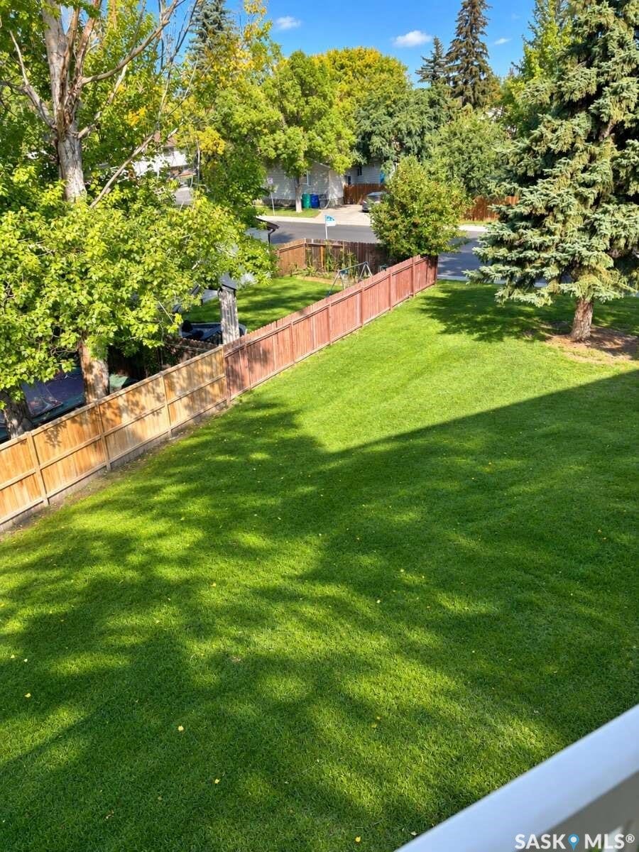 Expansive green lawn defined by a wood privacy fence and mature trees