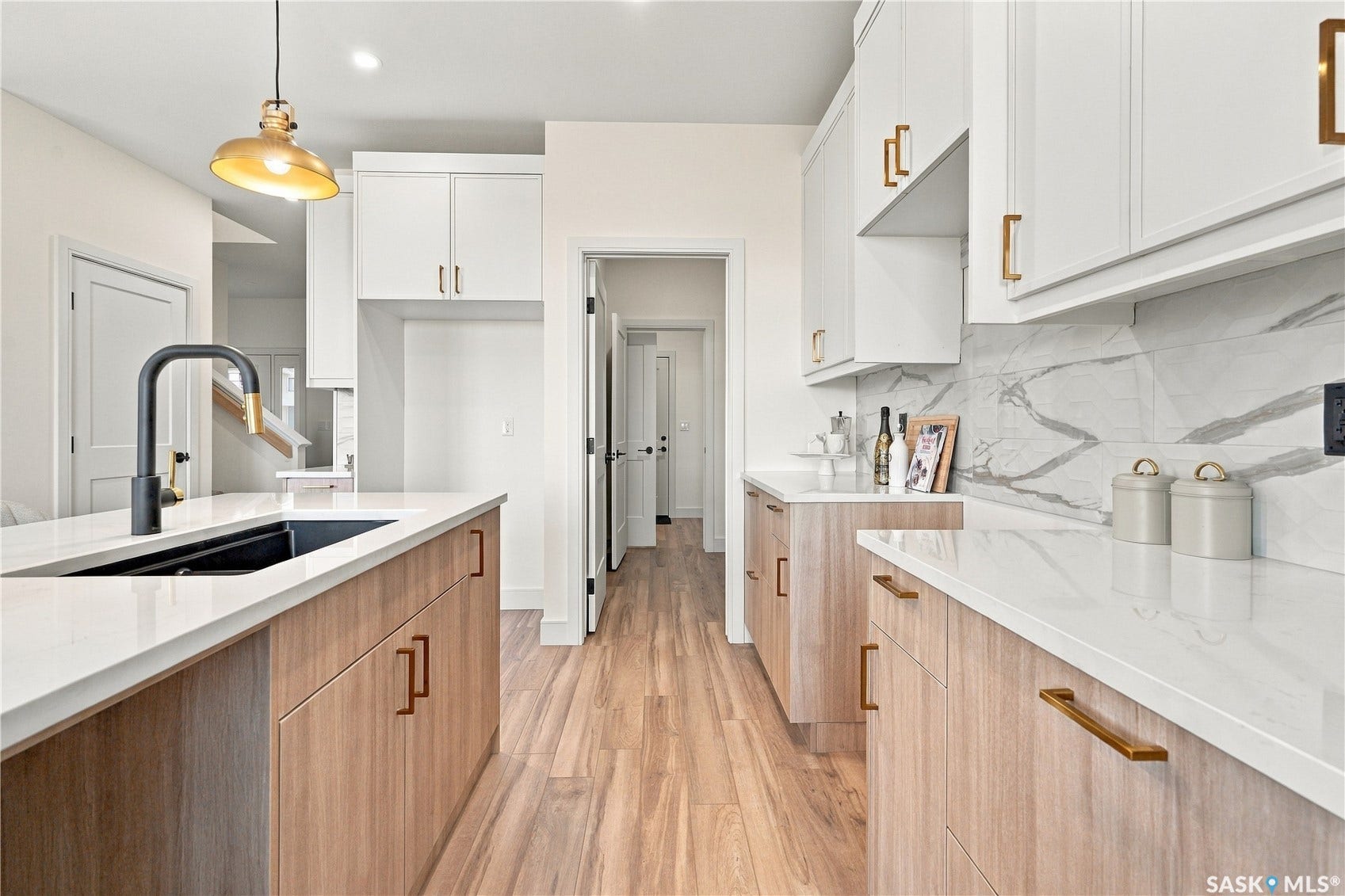 Expansive kitchen featuring white upper cabinetry, wood-finish lower cabinetry, white countertops, and a white and gray veined backsplash