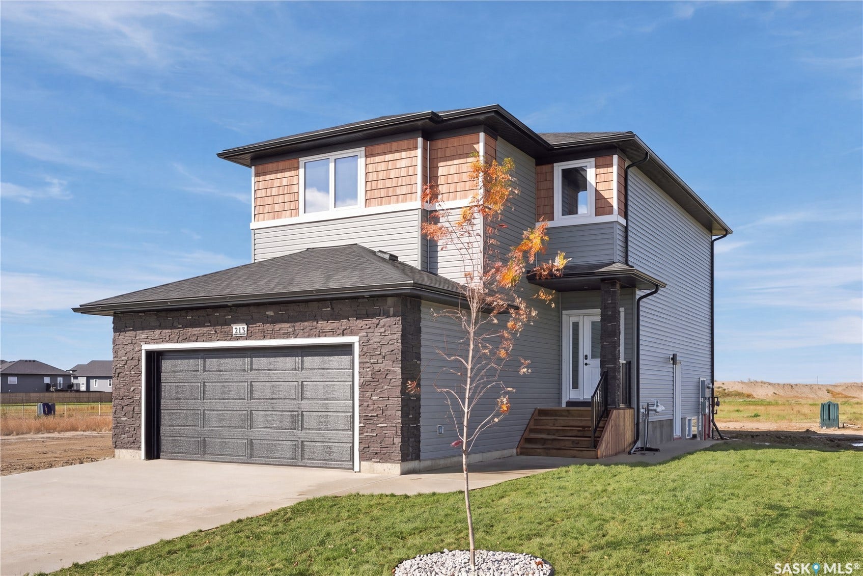 Two-story residence featuring a two-car garage, stone and siding exterior, and shingle roofing