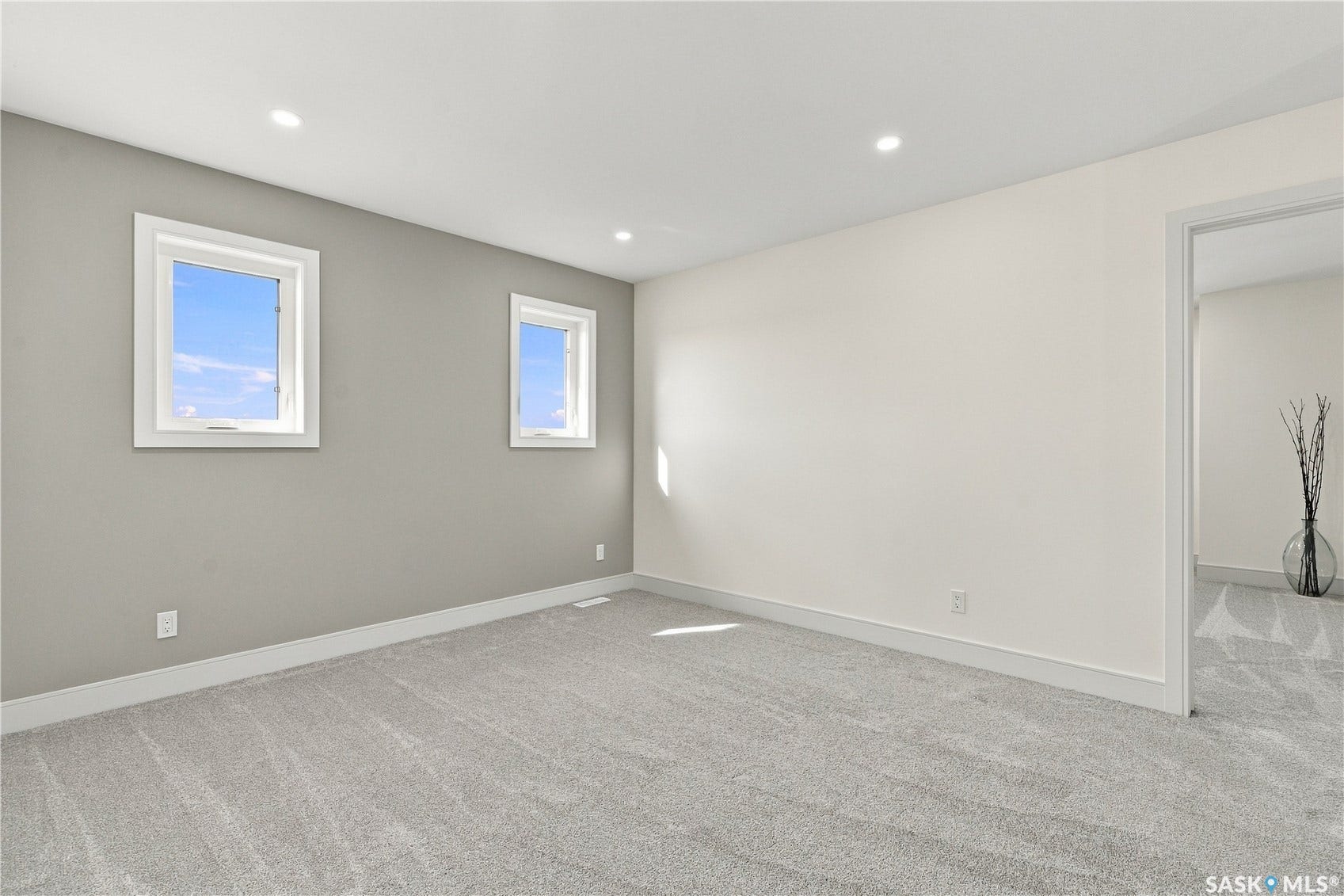 Recessed ceiling lighting, two windows, carpeted flooring, and a neutral color palette