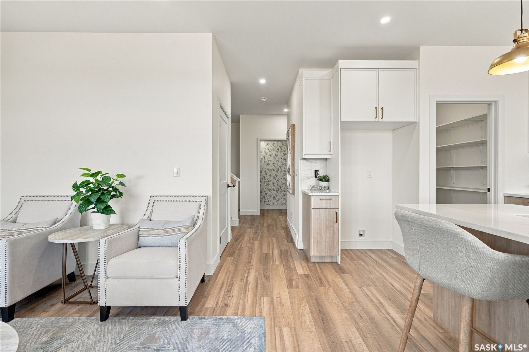 Wood-finish flooring throughout, white cabinetry with gold-tone hardware, and a built-in pantry with shelving