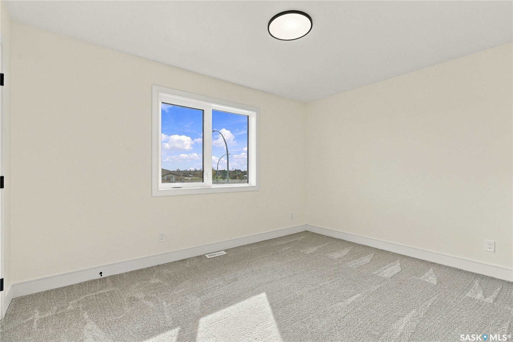 Neutral wall finishes with a large window, soft gray carpeting, and a modern flush-mount ceiling light