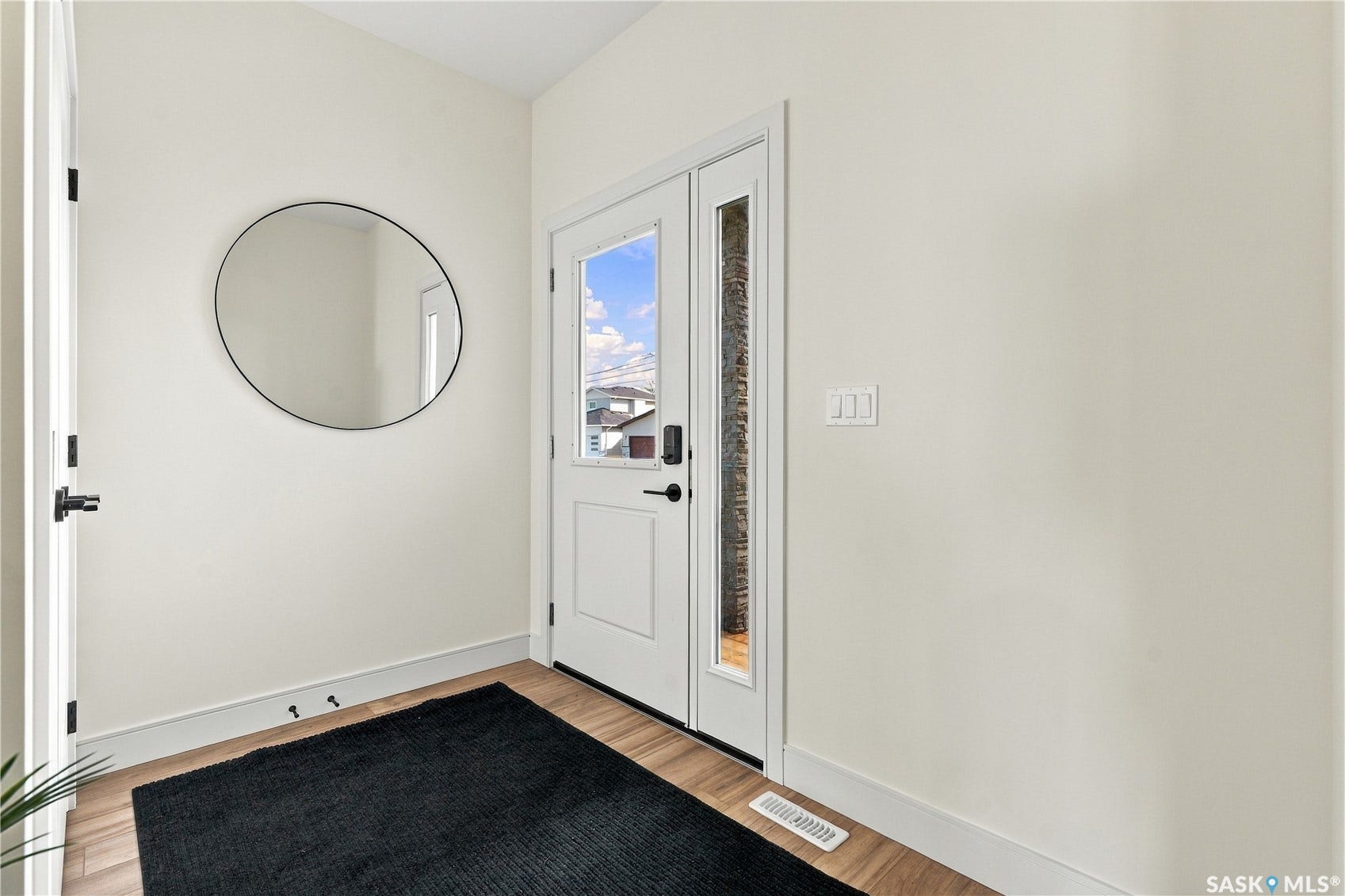 Entryway with wood-finish flooring, white trim, and a white paneled door with a full-length glass insert