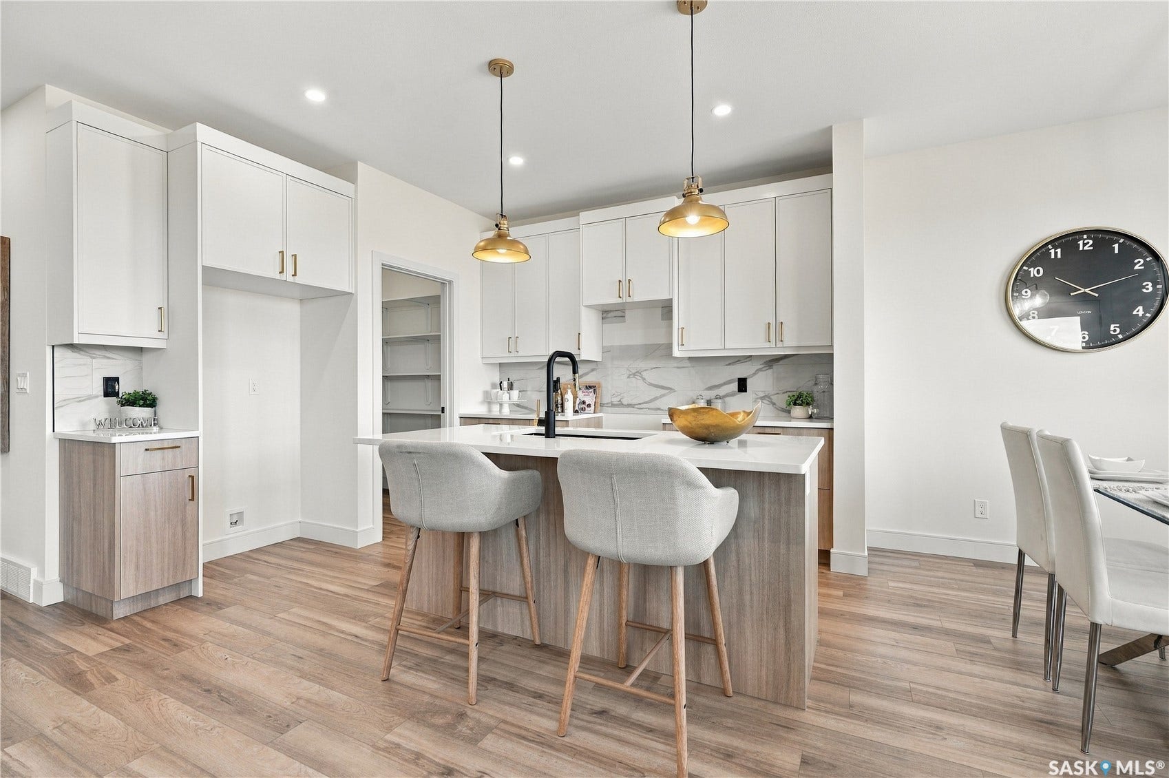 Modern kitchen featuring white cabinetry, wood-finish flooring, a central island with countertop seating, and recessed lighting