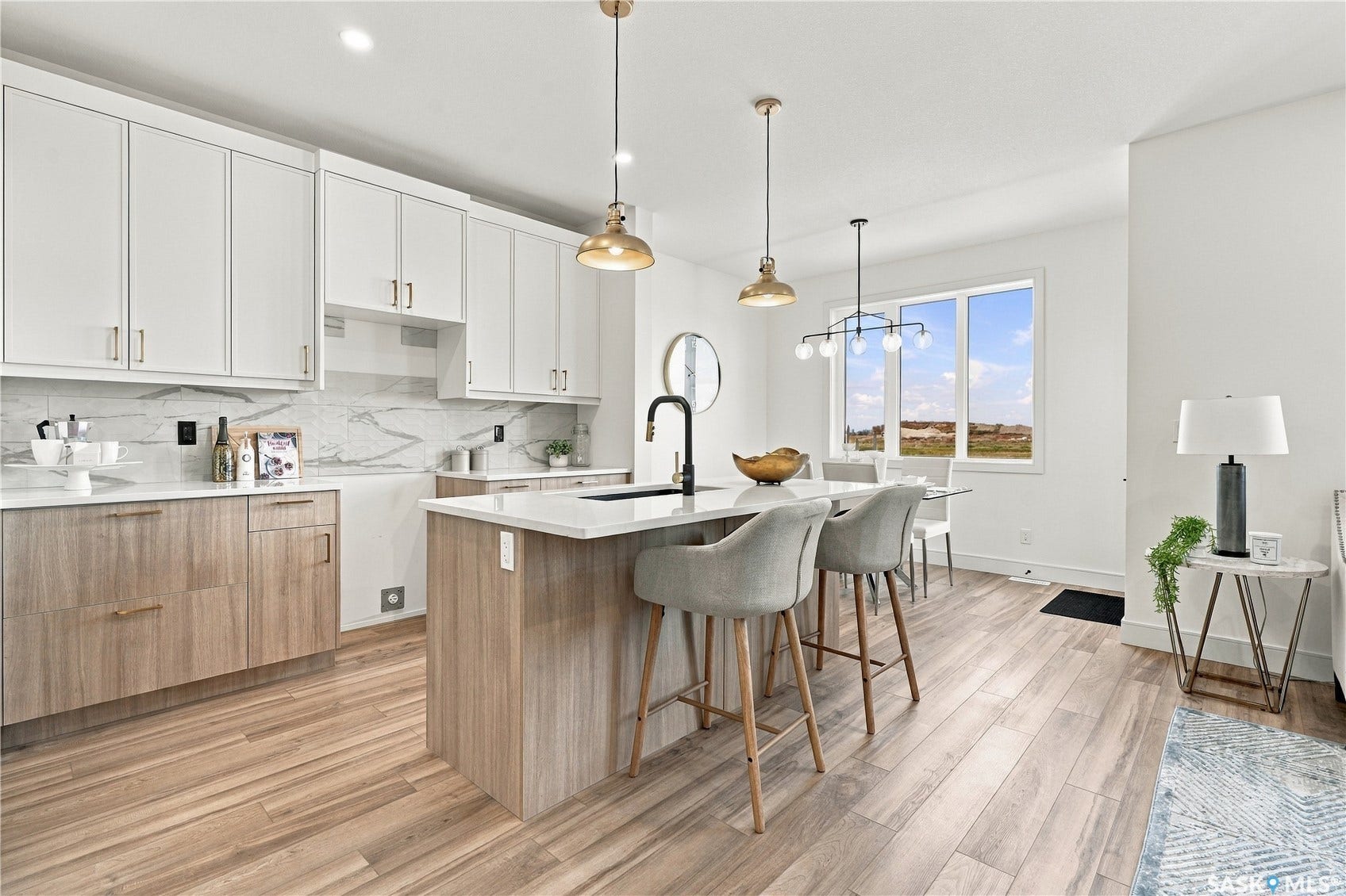 Kitchen featuring light wood-finish flooring, a central island with a white countertop, two-tone cabinetry, and pendant lighting