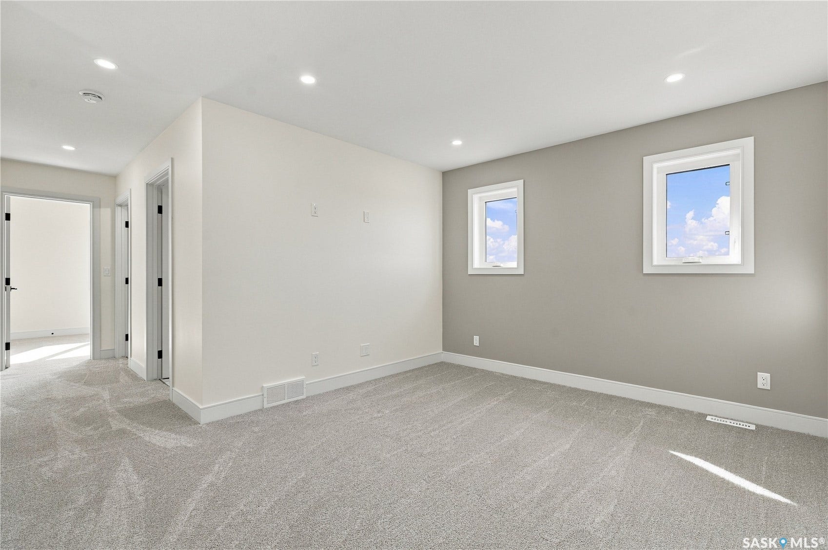 Plush gray carpeting, white painted walls, recessed ceiling lighting, and white trim throughout