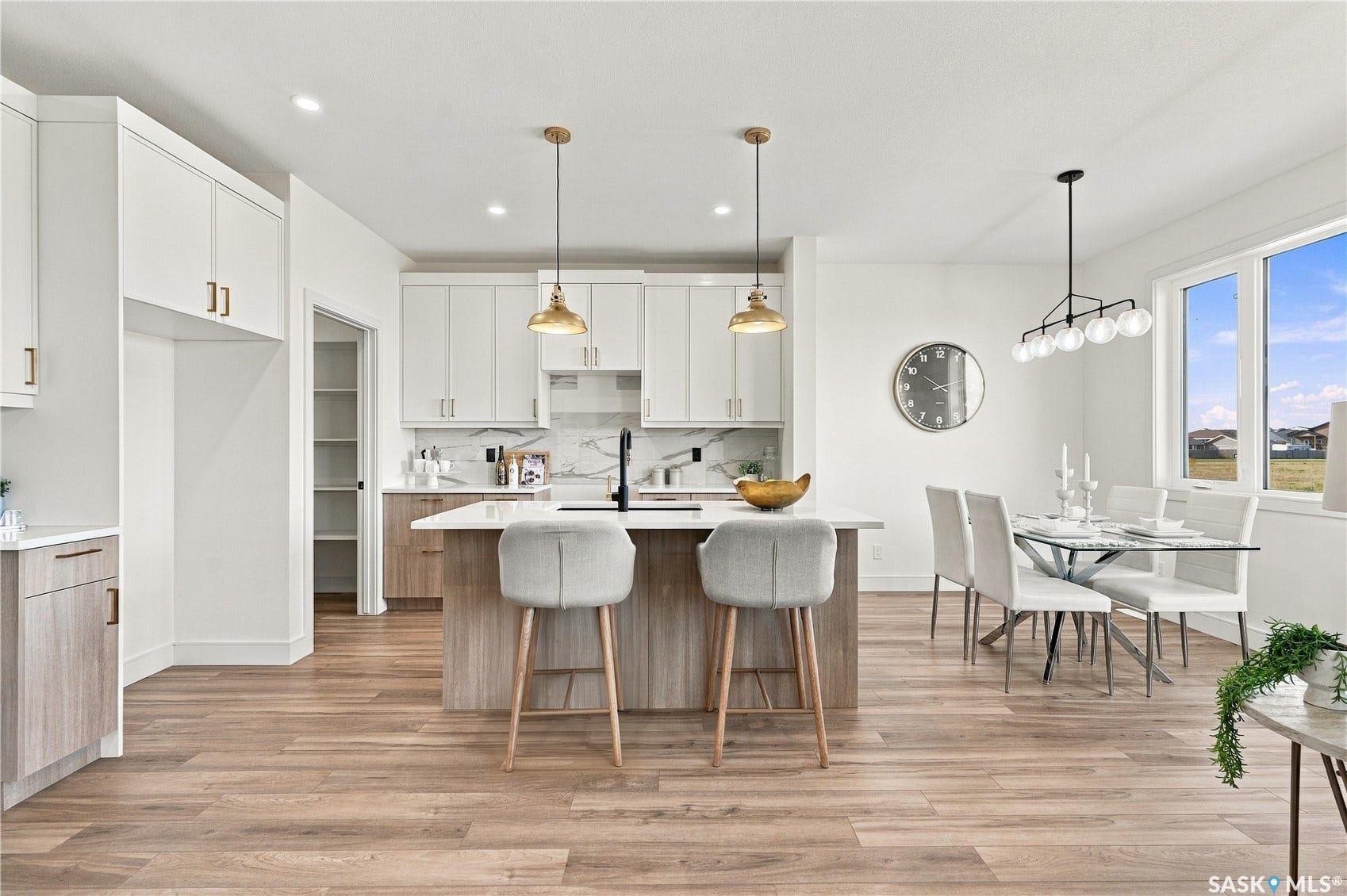 Modern kitchen featuring white and wood-finish cabinetry, a large center island with a white countertop, and wood-finish flooring