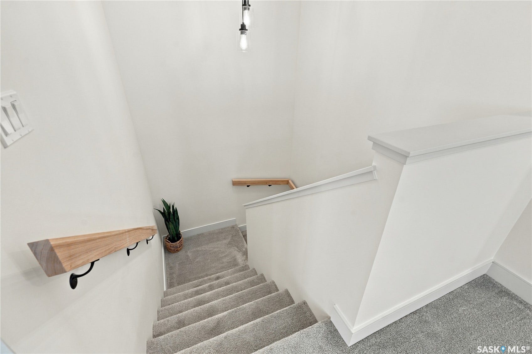 Carpeted staircase with contemporary wood handrails and pendant lighting