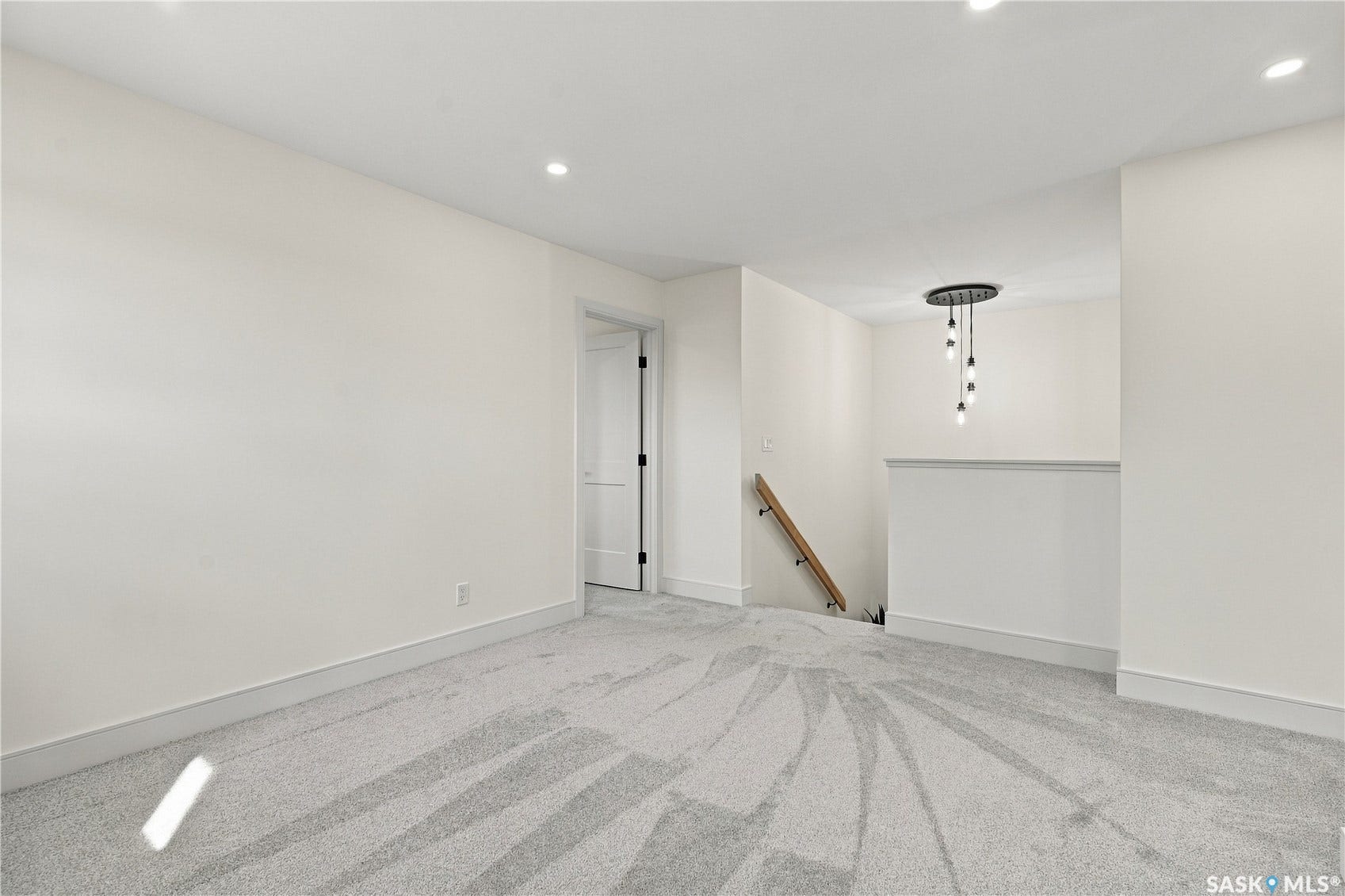 Recessed ceiling lighting, modern five-bulb chandelier, paneled interior door, light-toned carpet flooring, and white wall finishes
