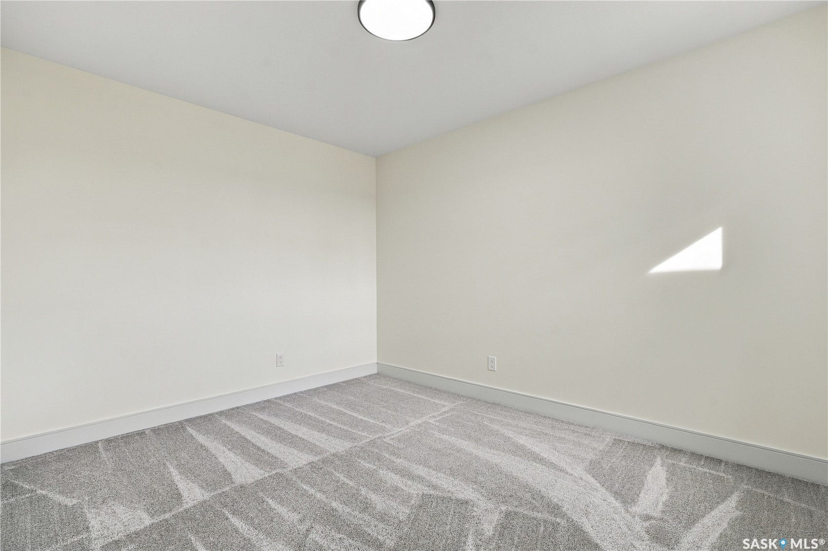 Neutral wall color with gray patterned carpeting and a flush-mount ceiling light