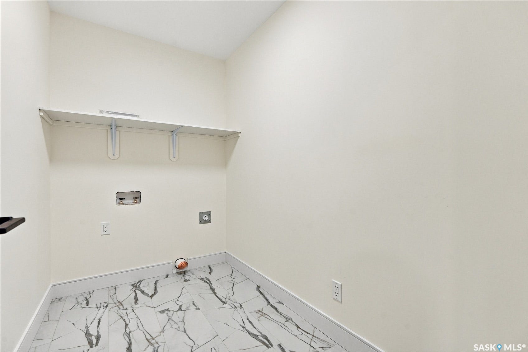 Utility room featuring a white wall shelf, white walls, and stone-finish flooring