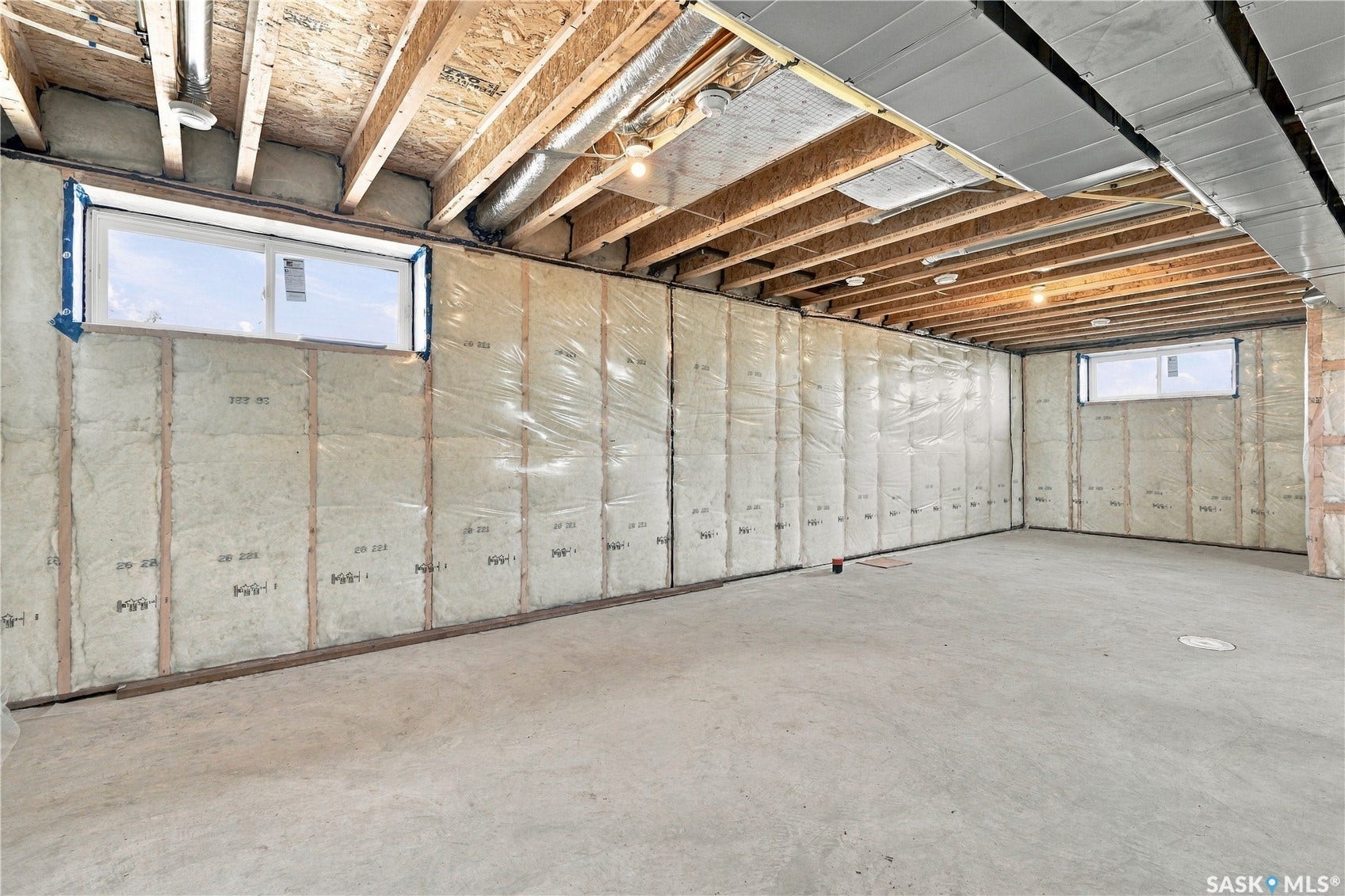 Unfinished basement with concrete flooring, exposed wood ceiling joists, and insulated perimeter walls