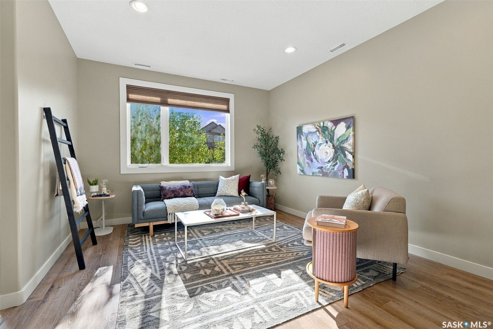 Recessed ceiling lighting, wood-finish flooring, neutral wall tones, large window with natural light, and clean white trim