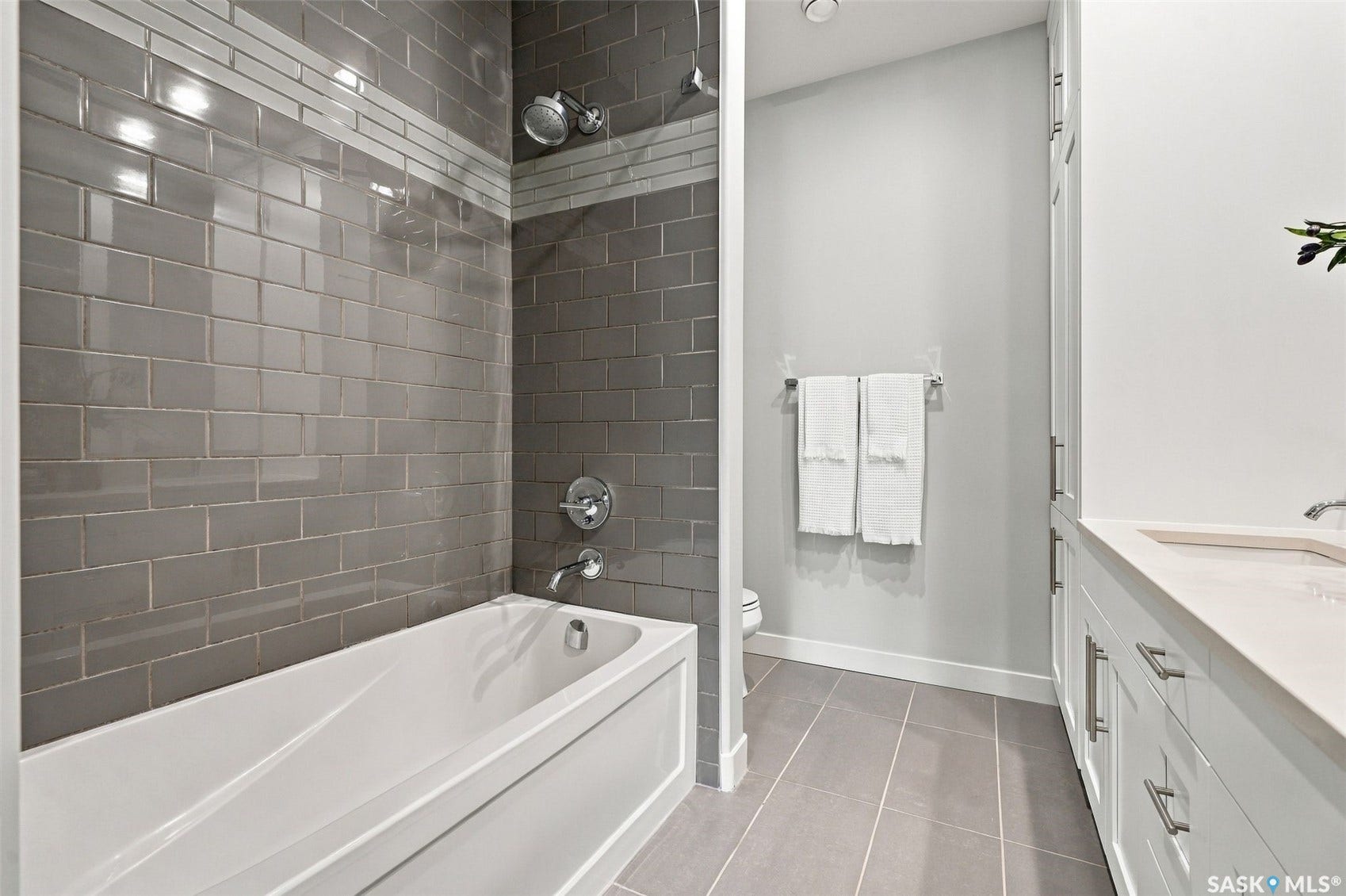 Bathtub with subway tile surround, integrated shower, single vanity with countertop, and floor tiling