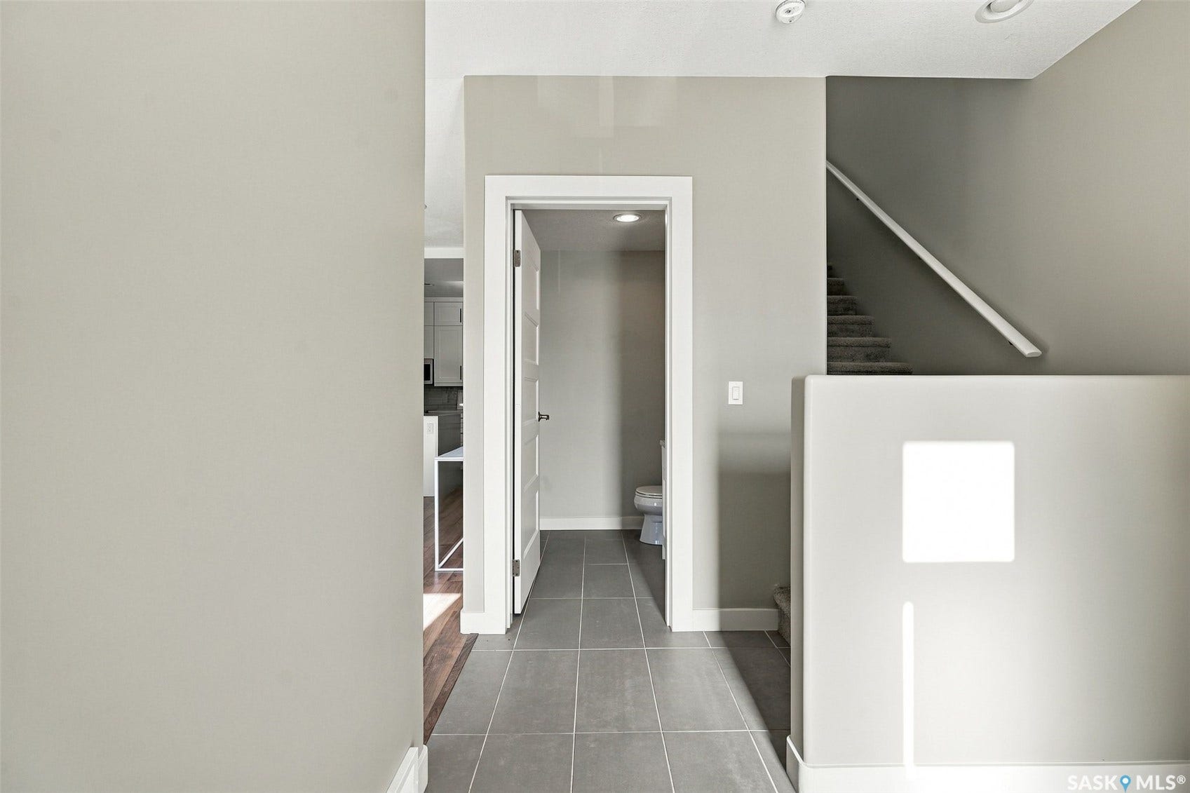 Recessed ceiling lighting, carpeted staircase, white handrail, gray tile flooring, and white interior doors