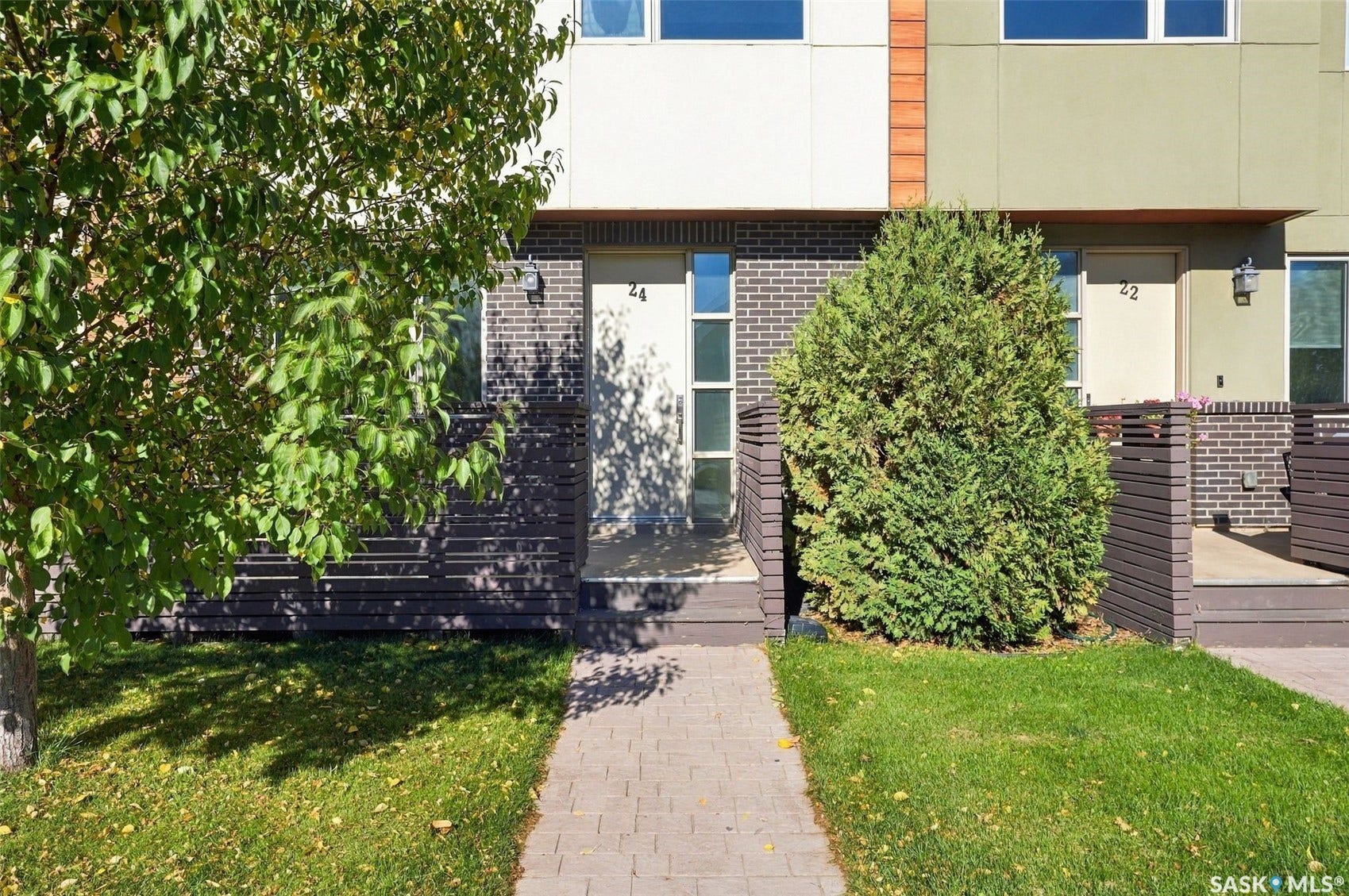Modern townhome with a brick and stucco facade, paver walkway, and a private front patio