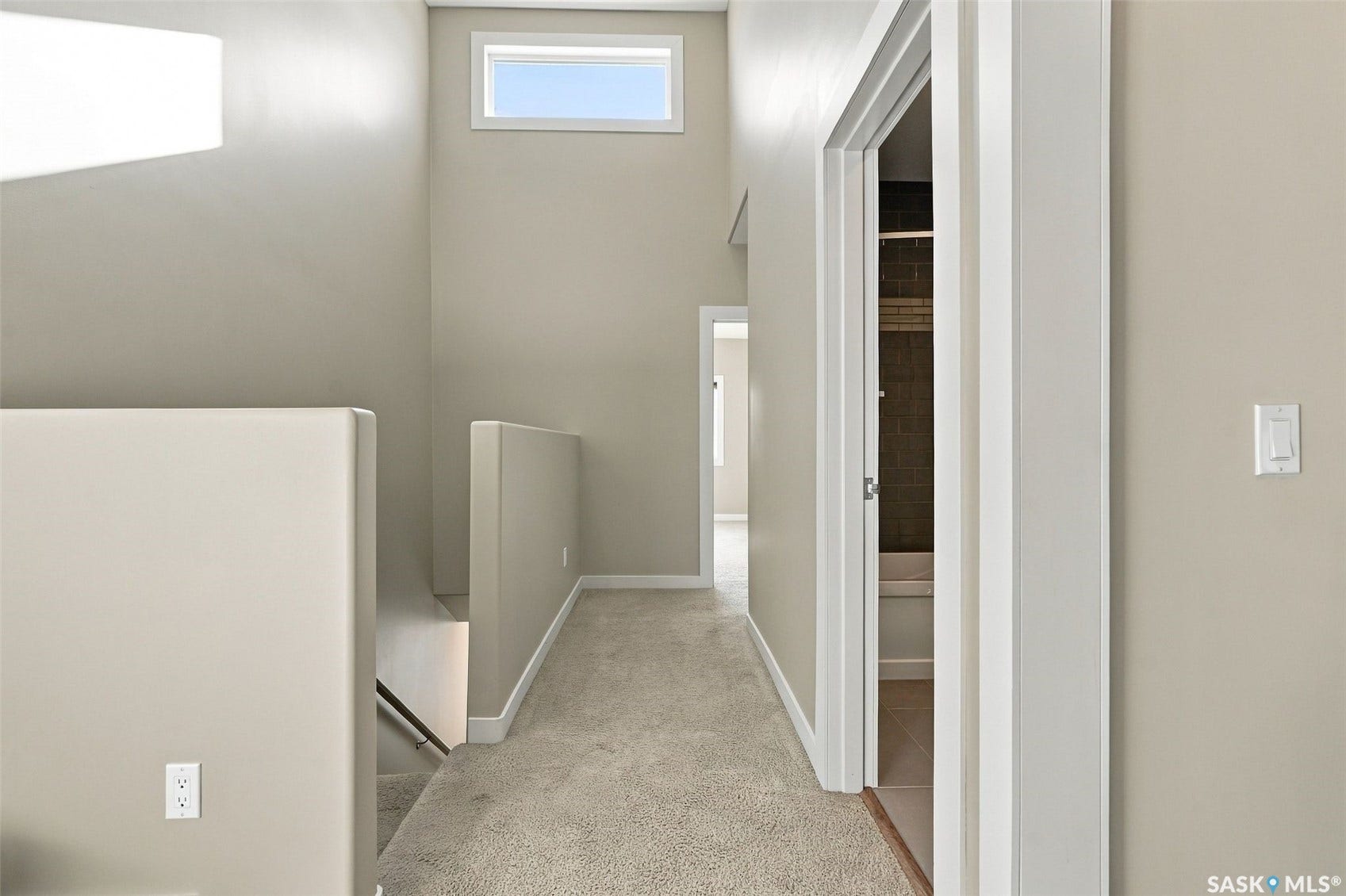 Hallway with carpet flooring, light neutral wall paint, and white trim