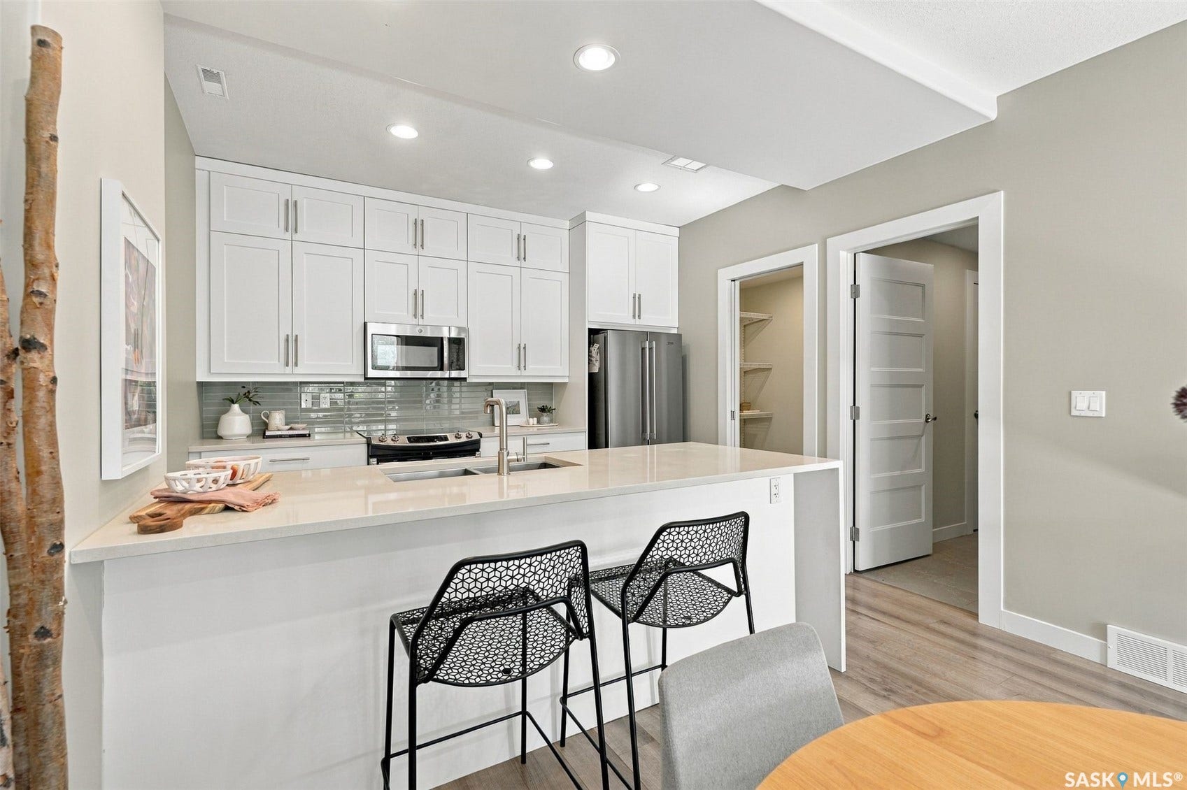 Kitchen featuring white cabinetry, stainless steel appliances, a light-toned countertop island, a tiled backsplash, and recessed lighting