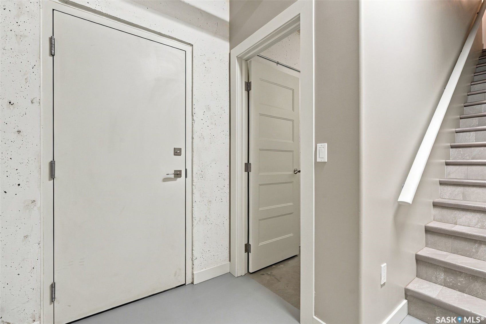 Gray tile flooring and a white handrail define the staircase