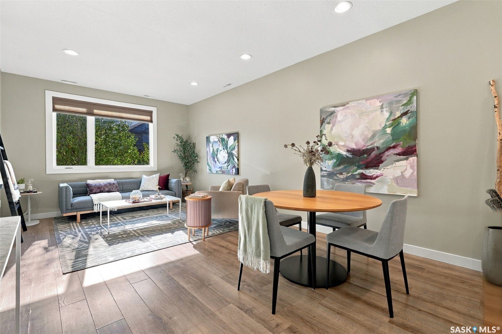 Open-concept living space featuring wood-finish flooring, recessed lighting, and a large window