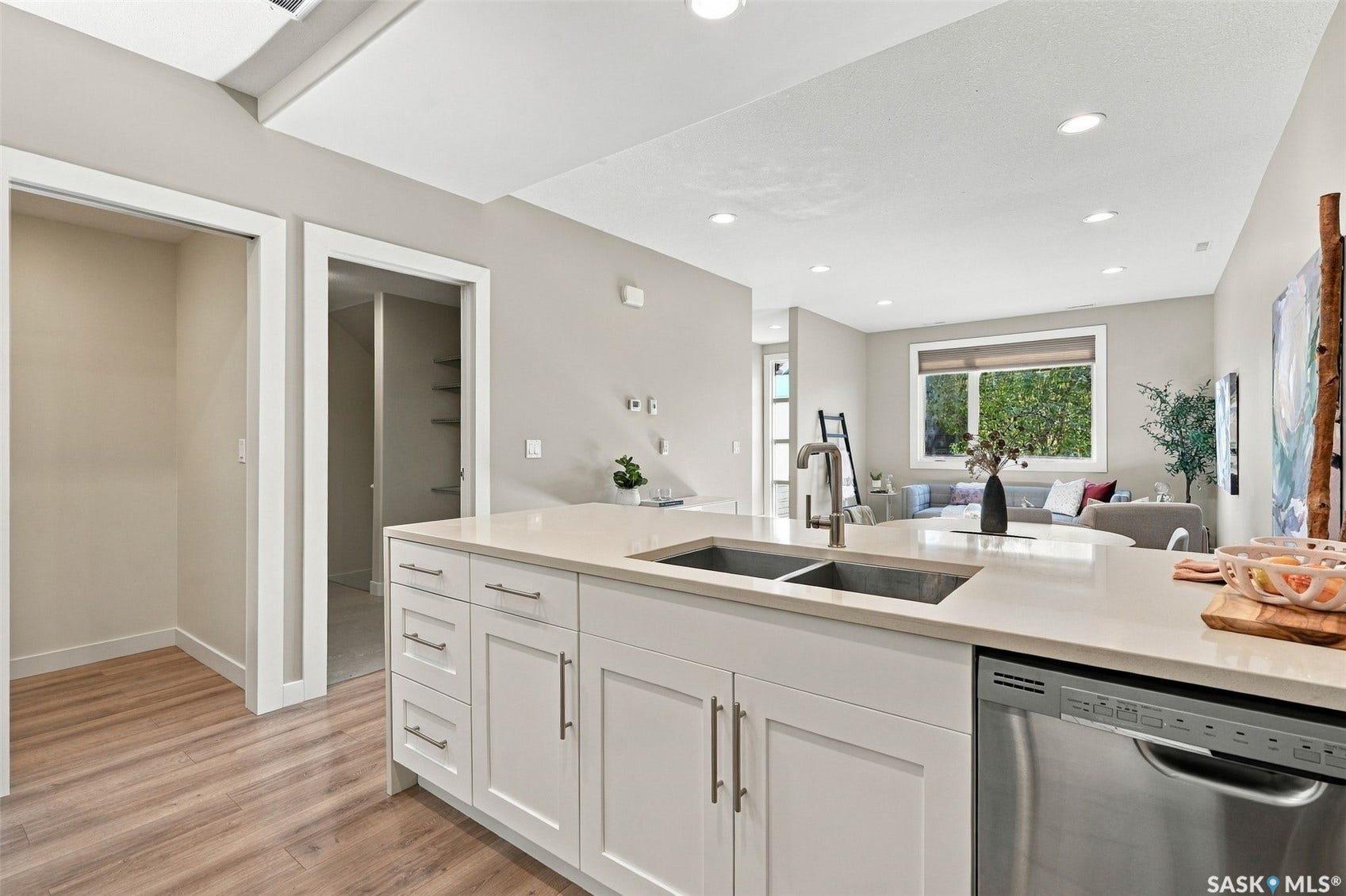 Modern kitchen featuring a large center island with white cabinetry, quartz countertop, and stainless steel appliances including a dishwasher