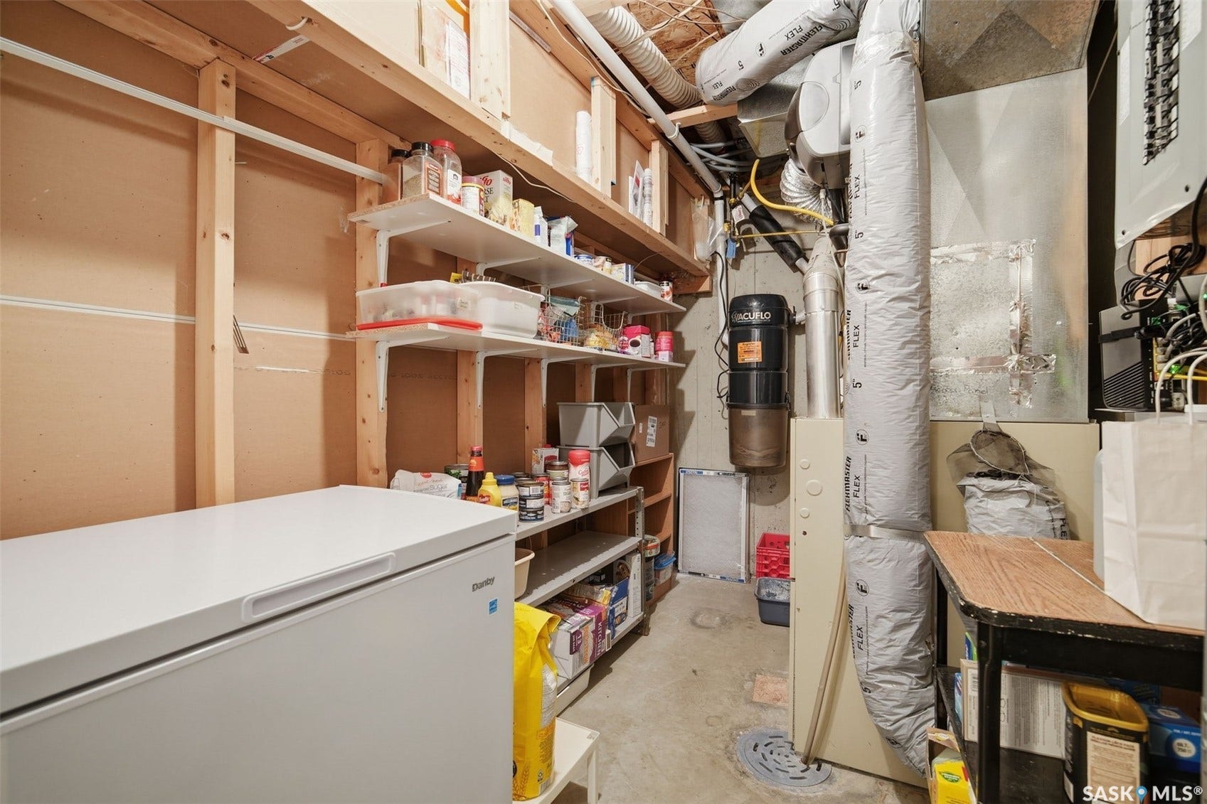 Utility room featuring built-in shelving, exposed ductwork, and electrical panel