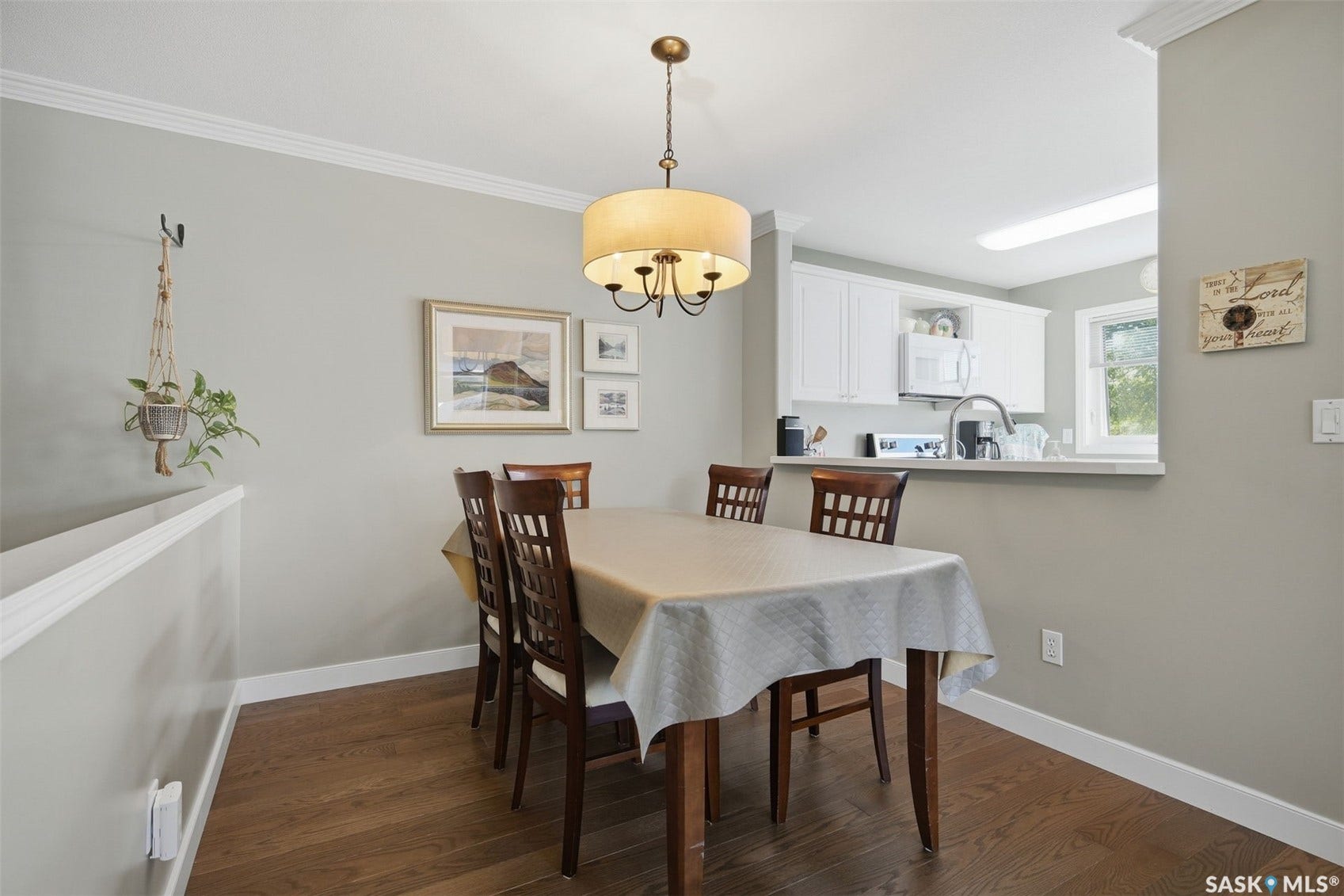 Open-concept dining area featuring wood-finish flooring, crown molding, and a drum-shade chandelier