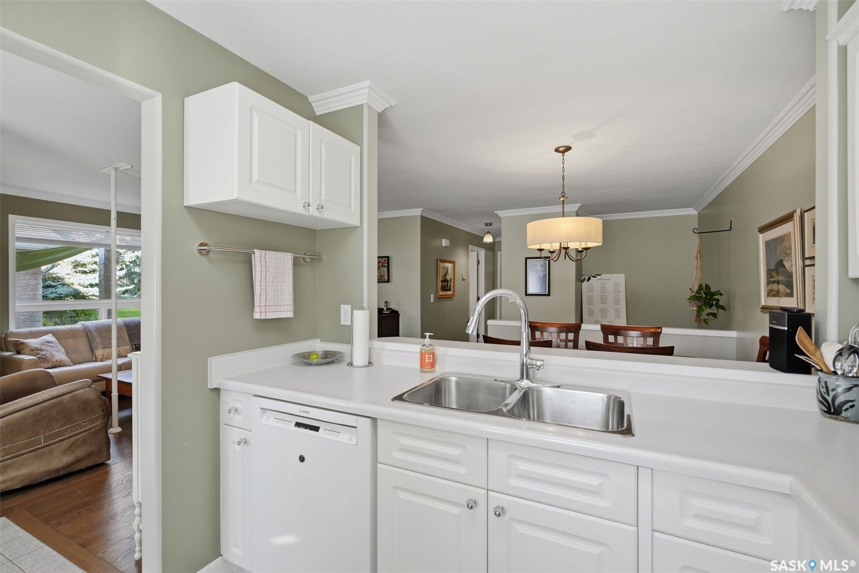 White cabinetry with chrome hardware, an integrated dishwasher, and a stainless steel double basin sink