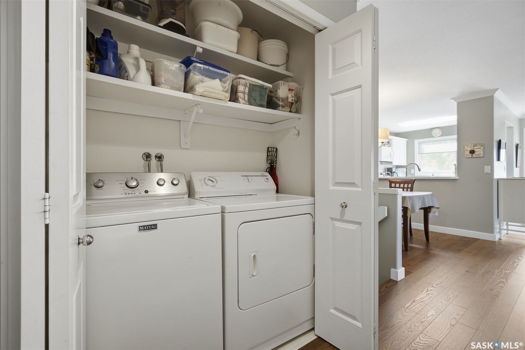 Integrated laundry area with shelving, hardwood flooring, and neutral wall tones