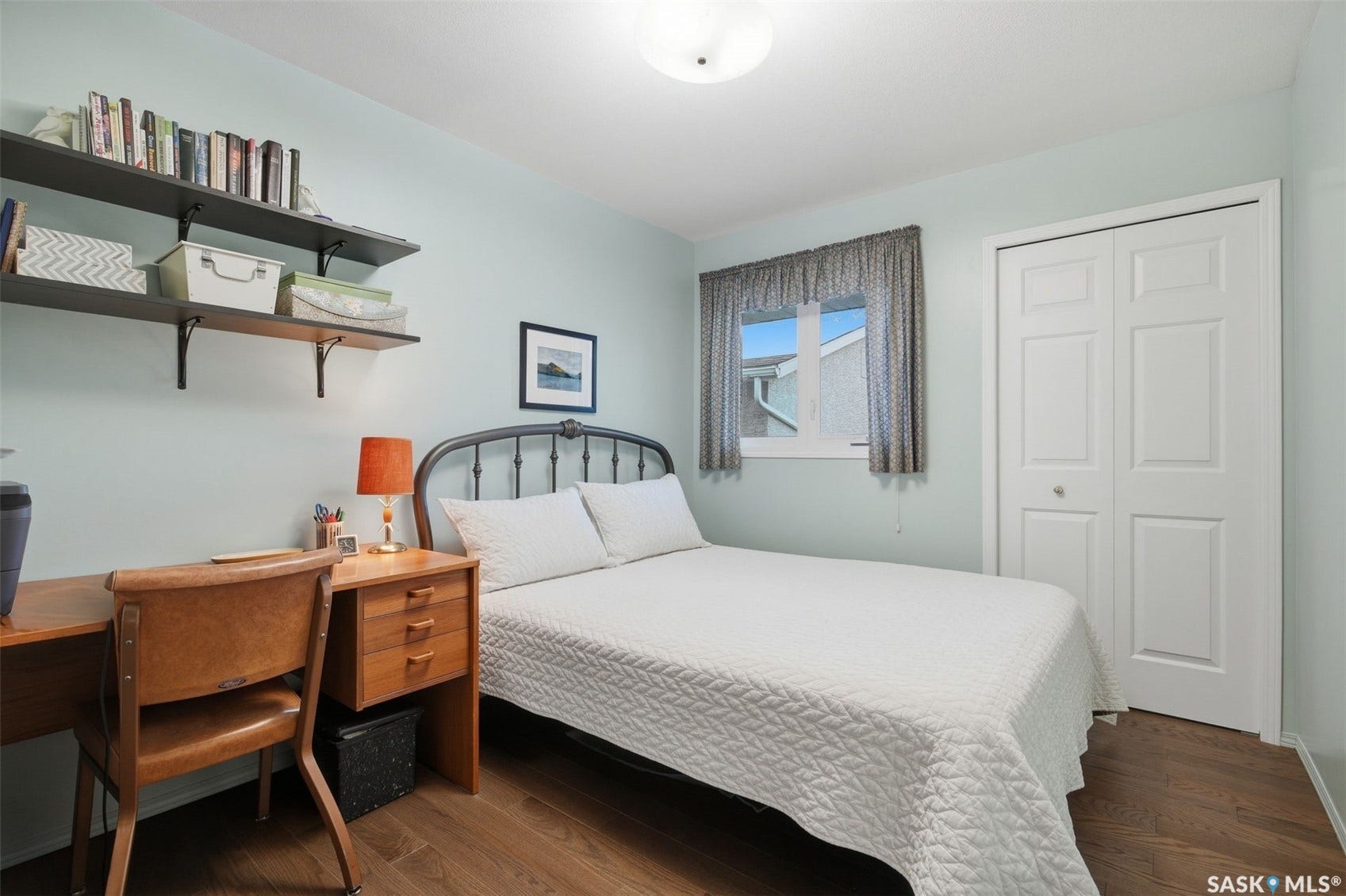 Wood-finish flooring, built-in shelving, paneled bi-fold closet doors, and a window with trim