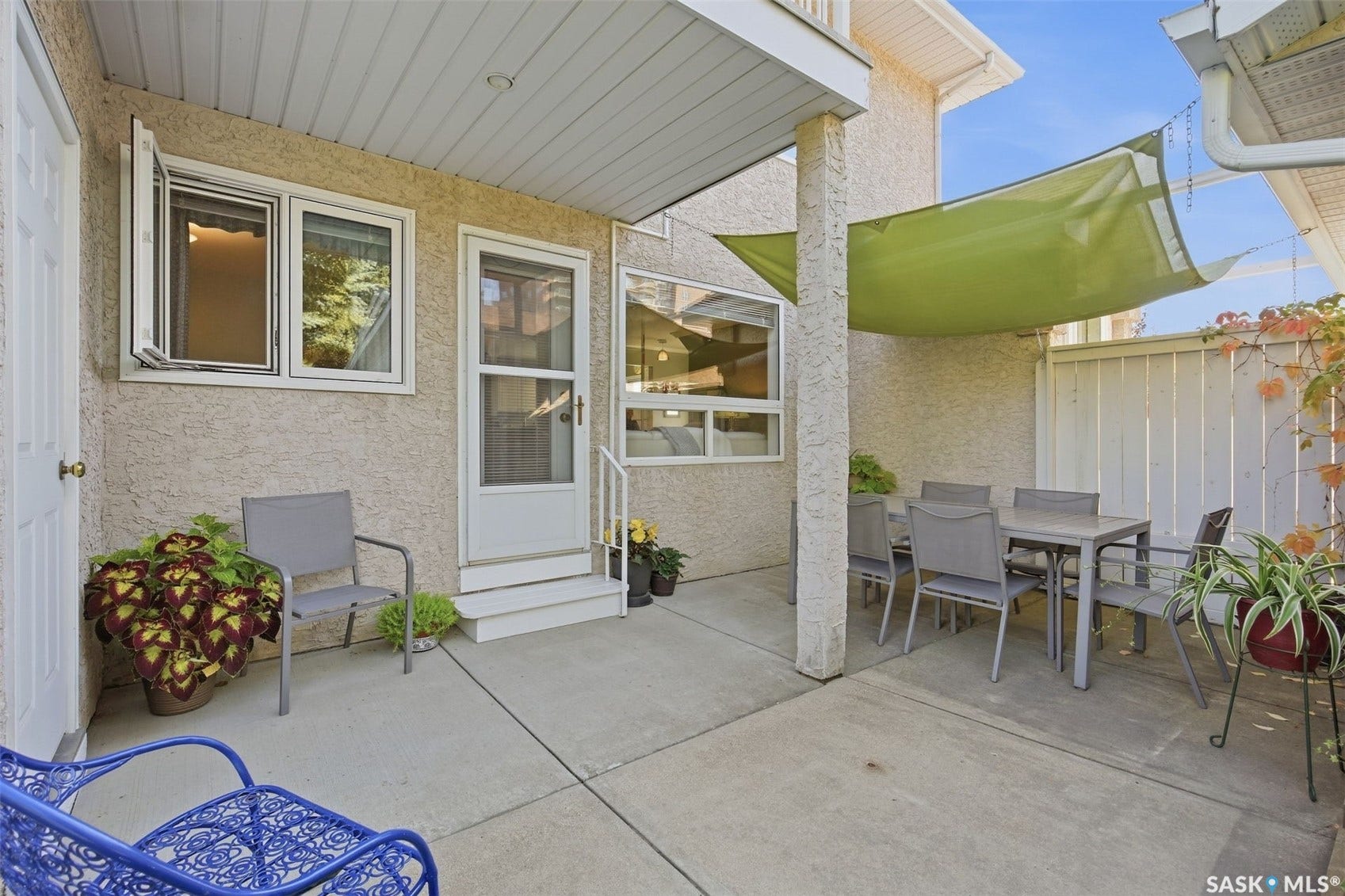 Private concrete patio with stucco exterior, white window frames, and a white fence