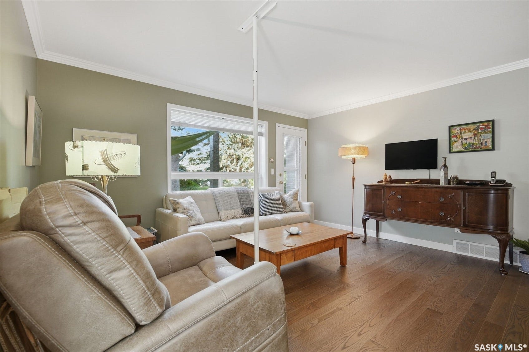 Hardwood flooring, crown molding, large window, and a door with an integrated blind