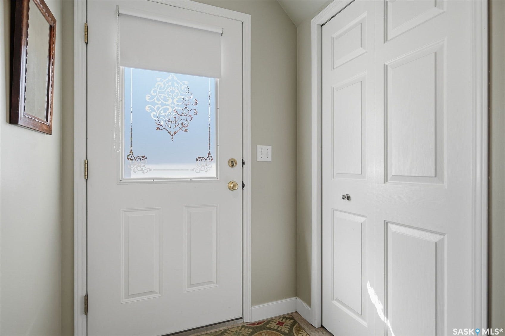 White panel door with frosted glass insert, featuring decorative etching, accompanied by a bi-fold closet door with panel detailing
