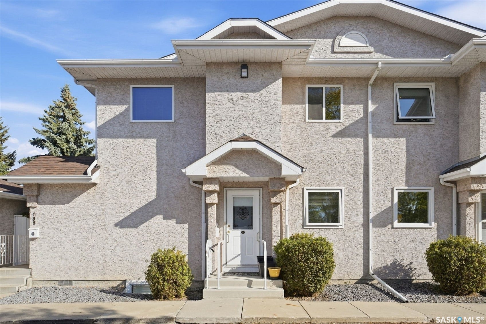 Stucco exterior with multiple windows, prominent gables, and a covered entry