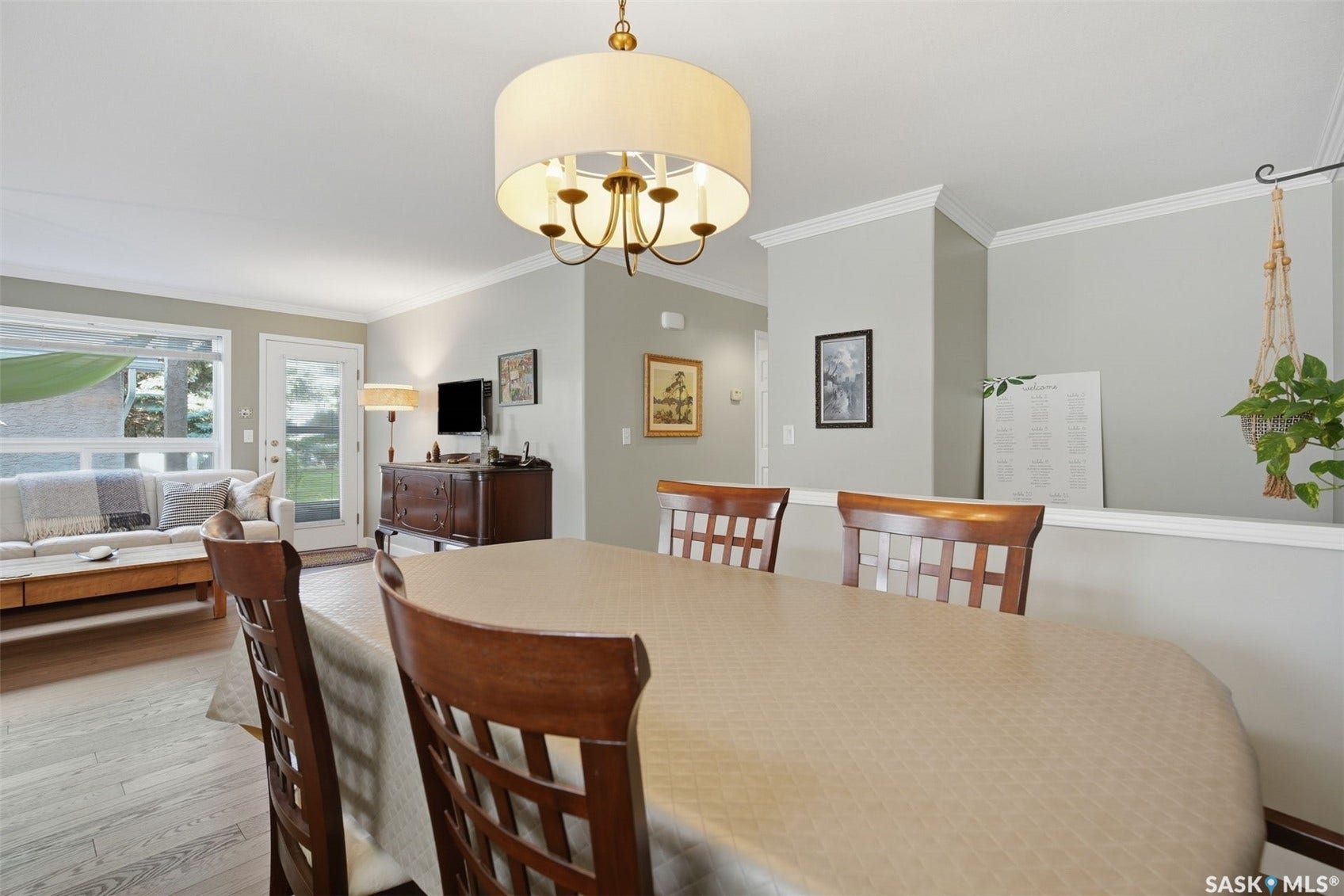 Dining area with drum pendant lighting, crown molding, and wood-finish flooring