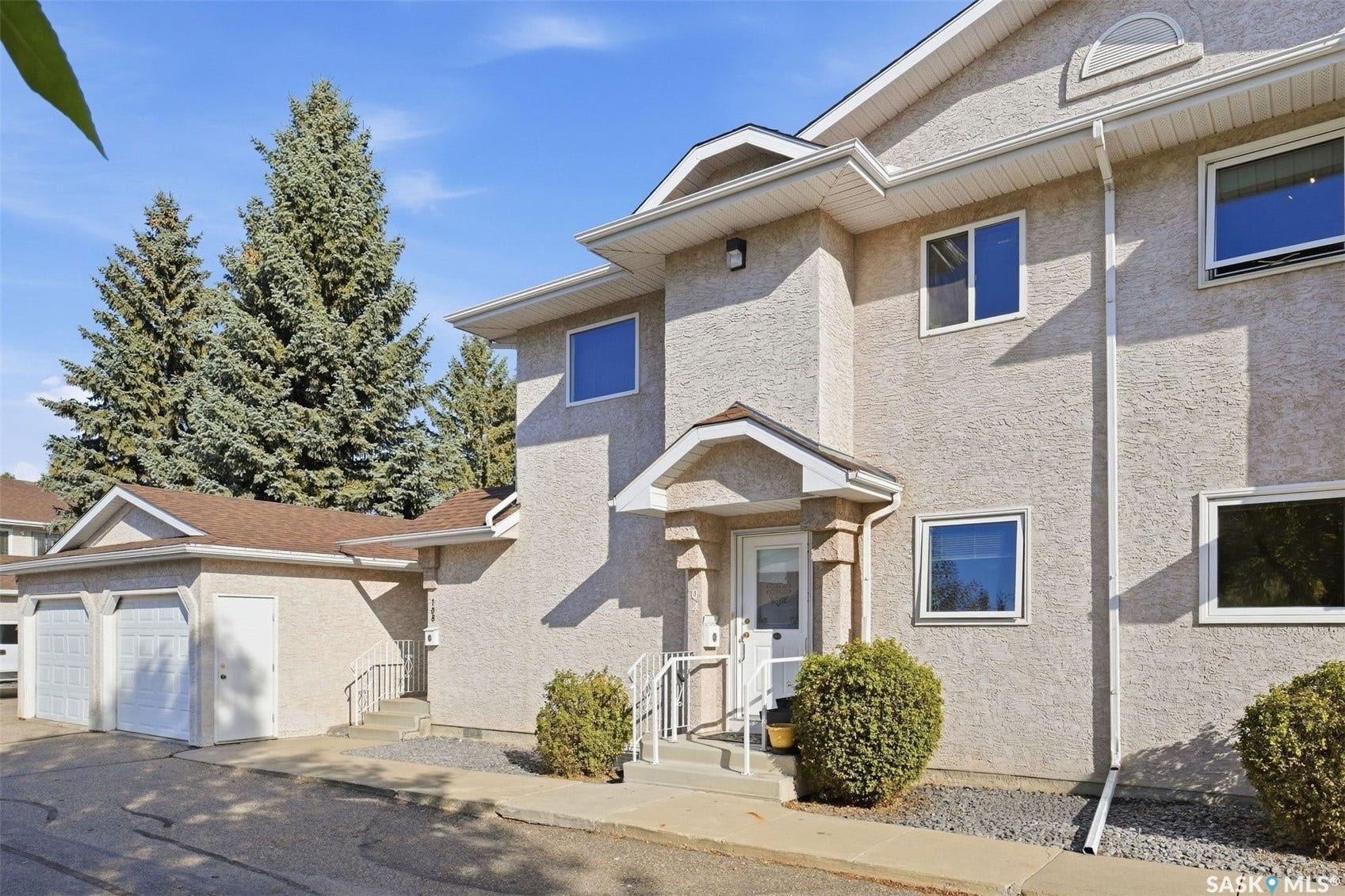 Stucco exterior with multiple windows, covered entry, and attached garage