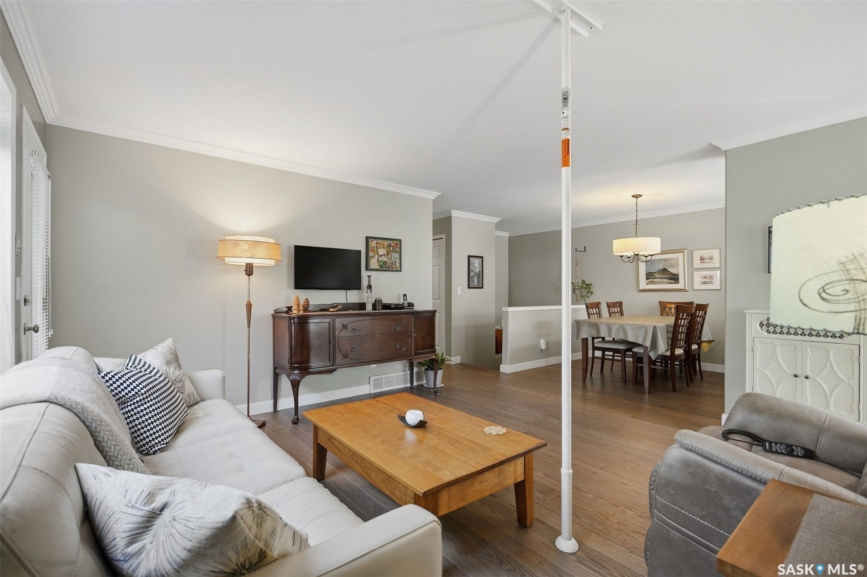 Hardwood-finish flooring throughout, crown molding, cased openings, and a dining area with a chandelier