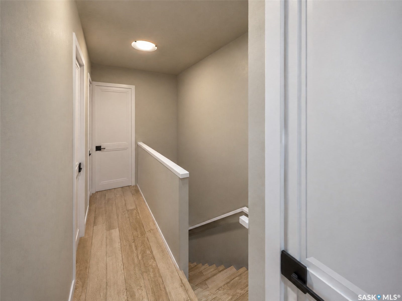 Hallway with wood-finish flooring, recessed lighting, and white panel doors with dark hardware