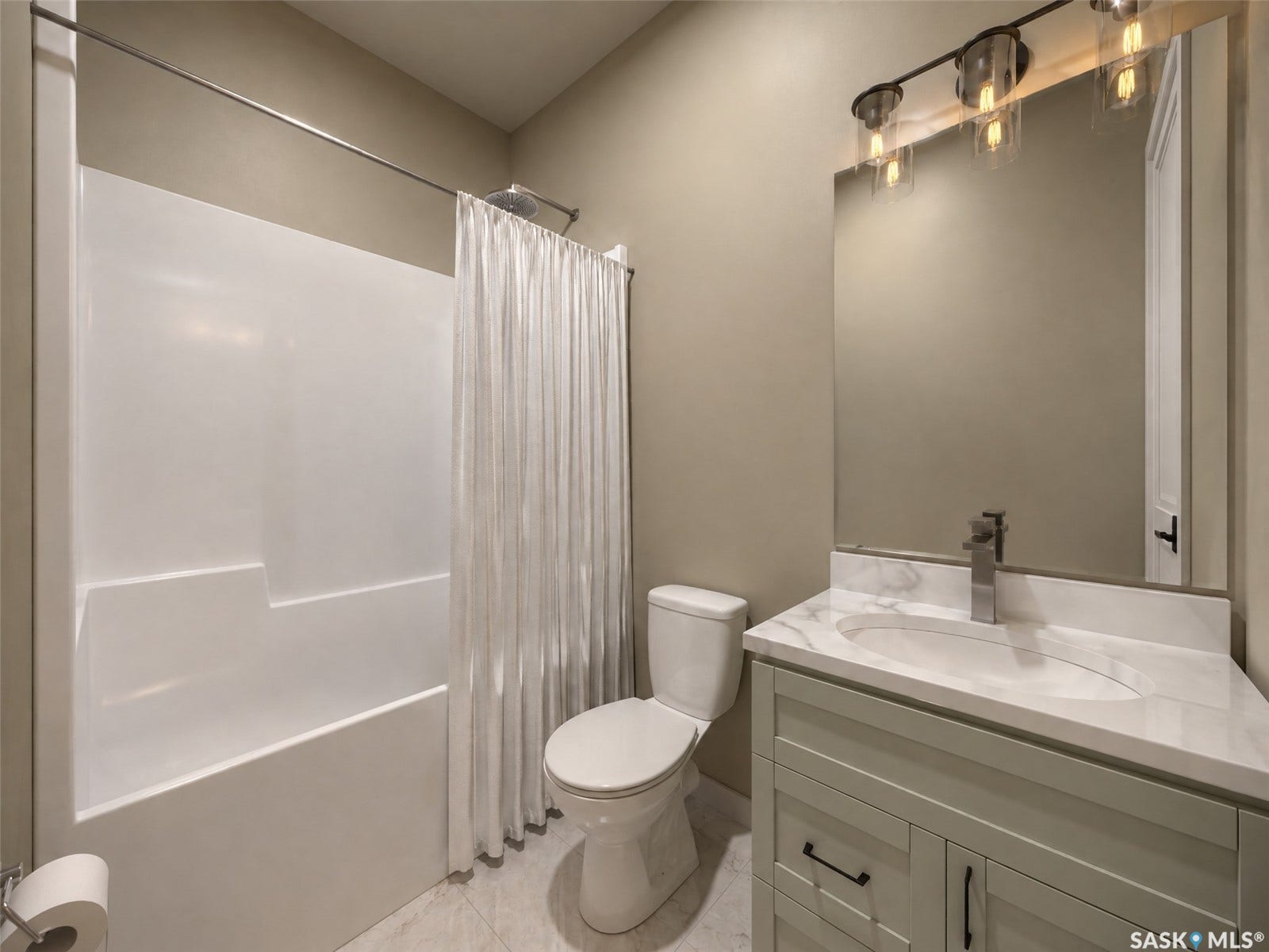 White tub-shower combination, single-sink vanity with white countertop, recessed oval basin, chrome faucet, and overhead linear light fixture
