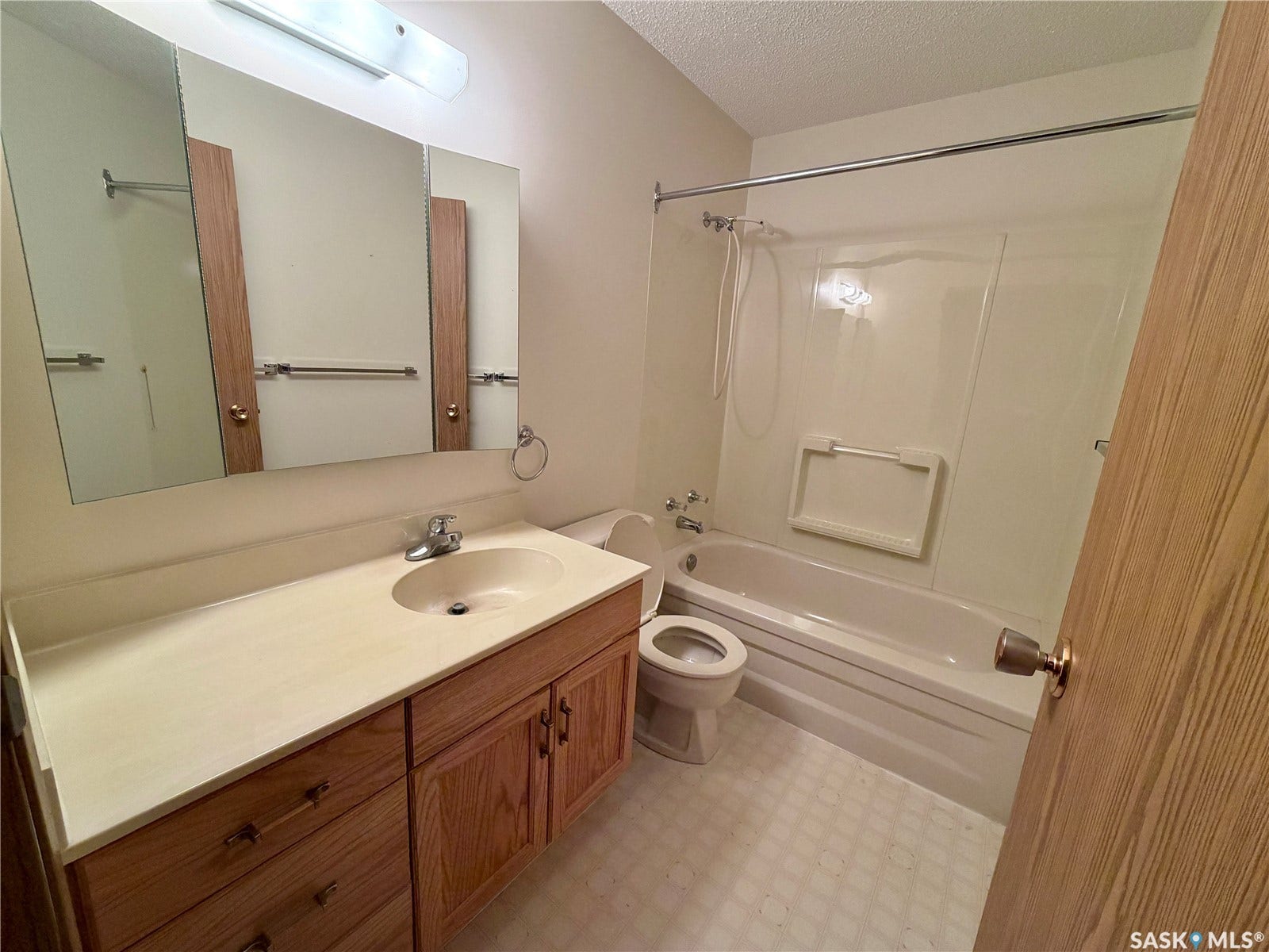 305 1st Street W, #301, Rosetown SK S0L 2V0 Vanity with integrated sink and wood-finish cabinetry, tri-fold mirror, and full-size bathtub with shower kit