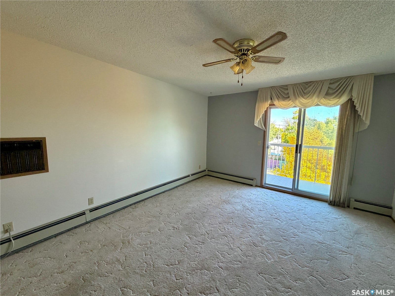 305 1st Street W, #301, Rosetown SK S0L 2V0 Sliding glass door leading to a balcony, ceiling fan with integrated lighting, textured ceiling, and carpet flooring