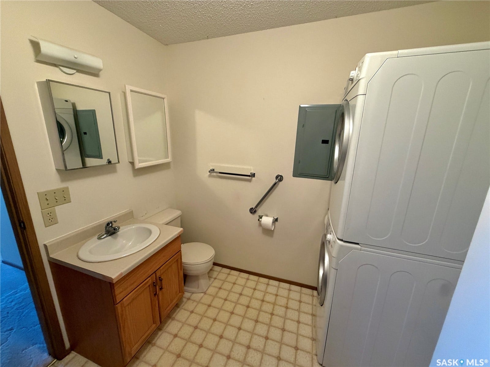 305 1st Street W, #301, Rosetown SK S0L 2V0 Vanity with a single basin sink, built-in storage cabinet, and stacked laundry appliances