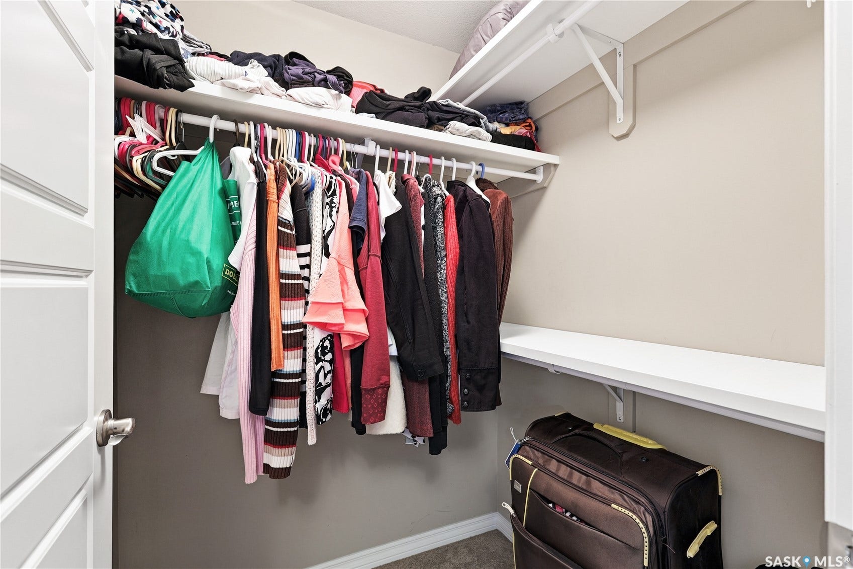 Walk-in closet featuring multiple white shelves and hanging rods
