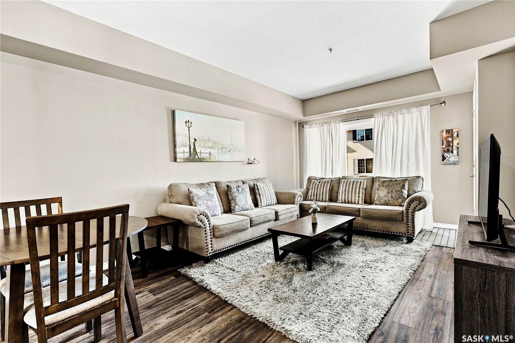Bright, open living area anchored by wood-finish flooring and neutral wall tones