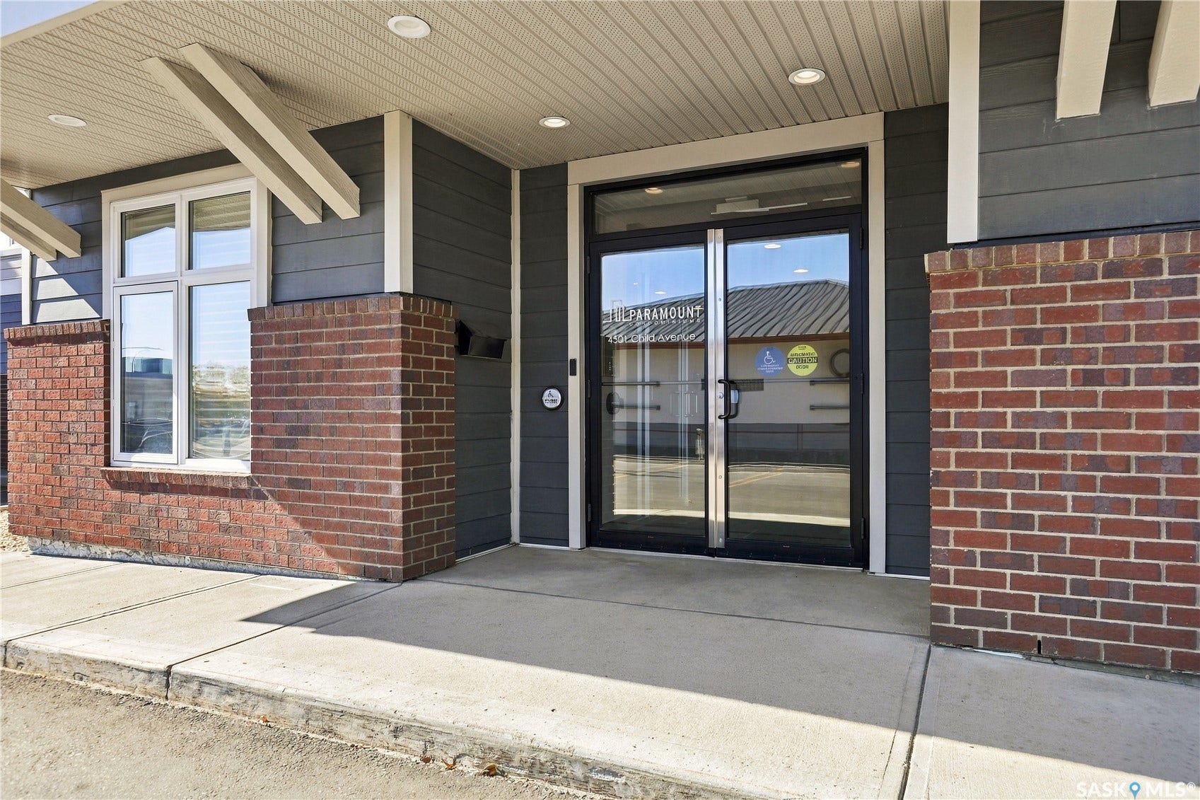 Brick and horizontal siding exterior with a concrete sidewalk and double glass entry doors